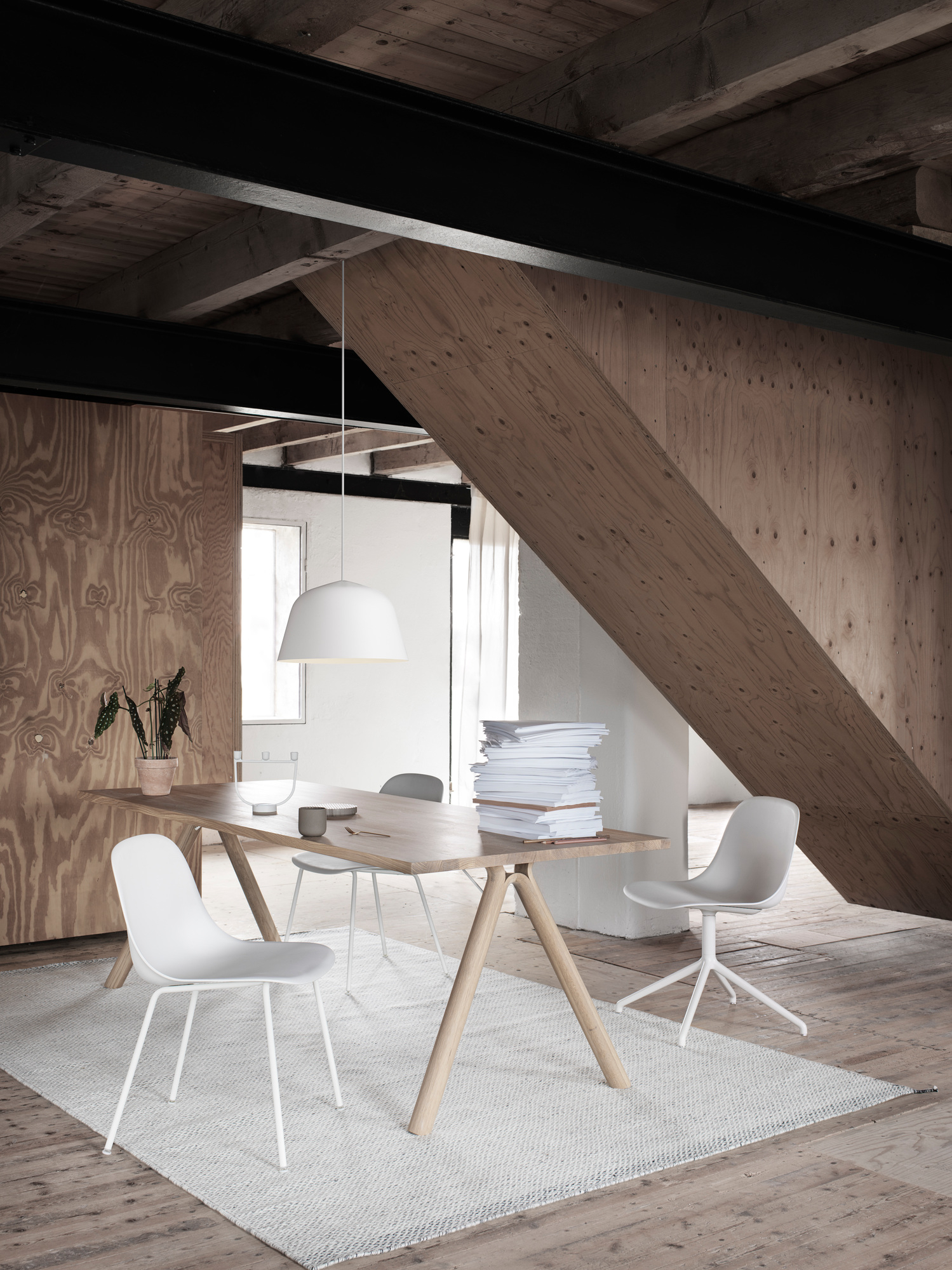 Heller Raum mit Holzwänden, Esstisch und mehreren Fiber Side Chairs von Muuto mit Drehfuß.