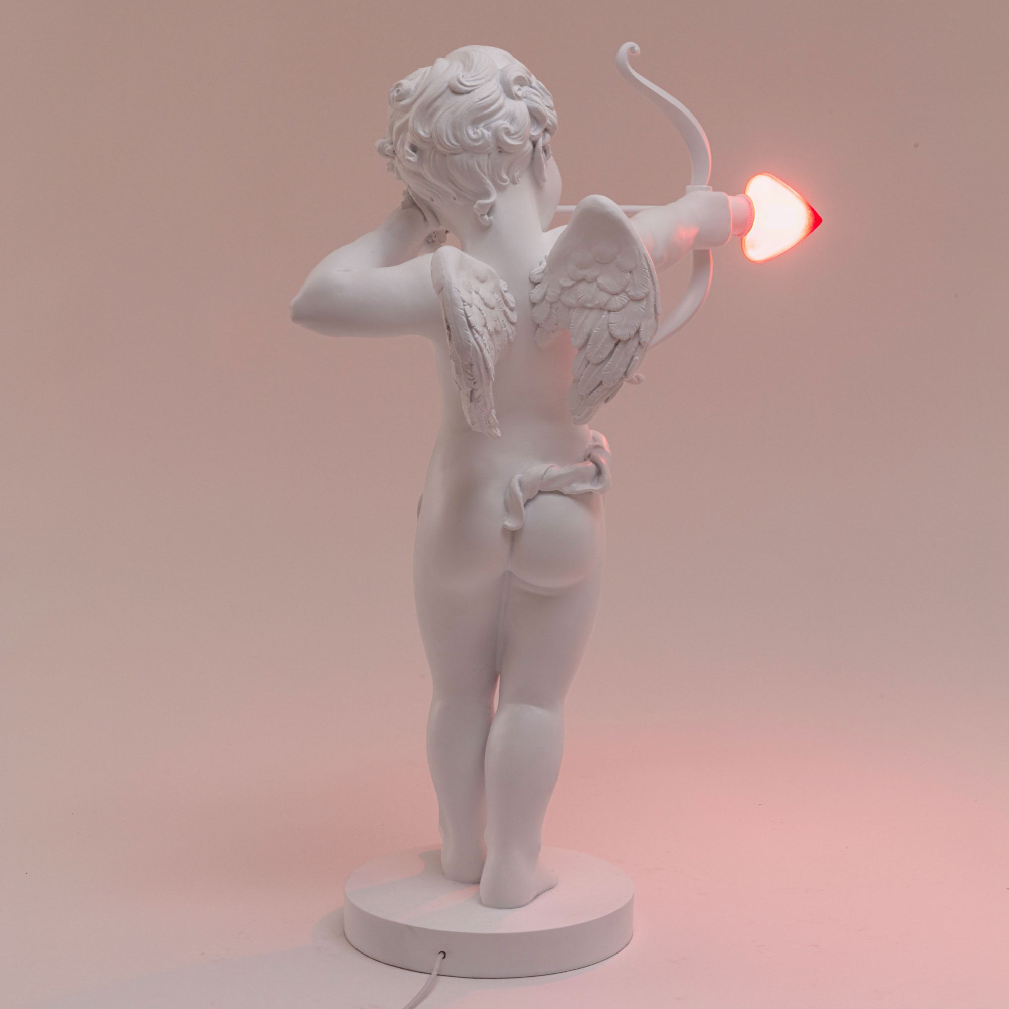 Rückansicht der Seletti Cupid Lampe, Amor Figur mit Pfeil als Leuchtmittel.