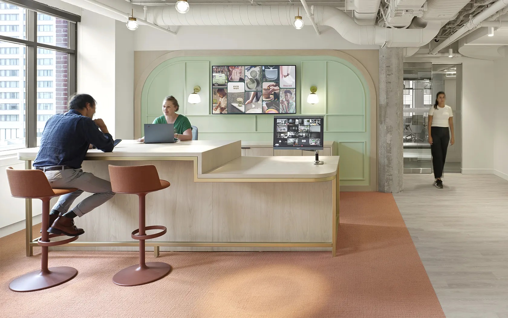Hula Barhocker von Andreu World in modernem Büro, braune Sitzschale und Fußstütze, zwei Personen sitzen.