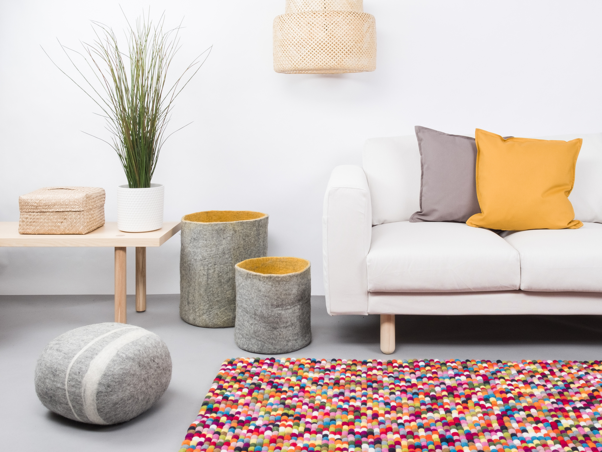 Farbenfroher Filzkugel Teppich von myfelt im Wohnzimmer mit Sofa, Tisch und Dekoration.
