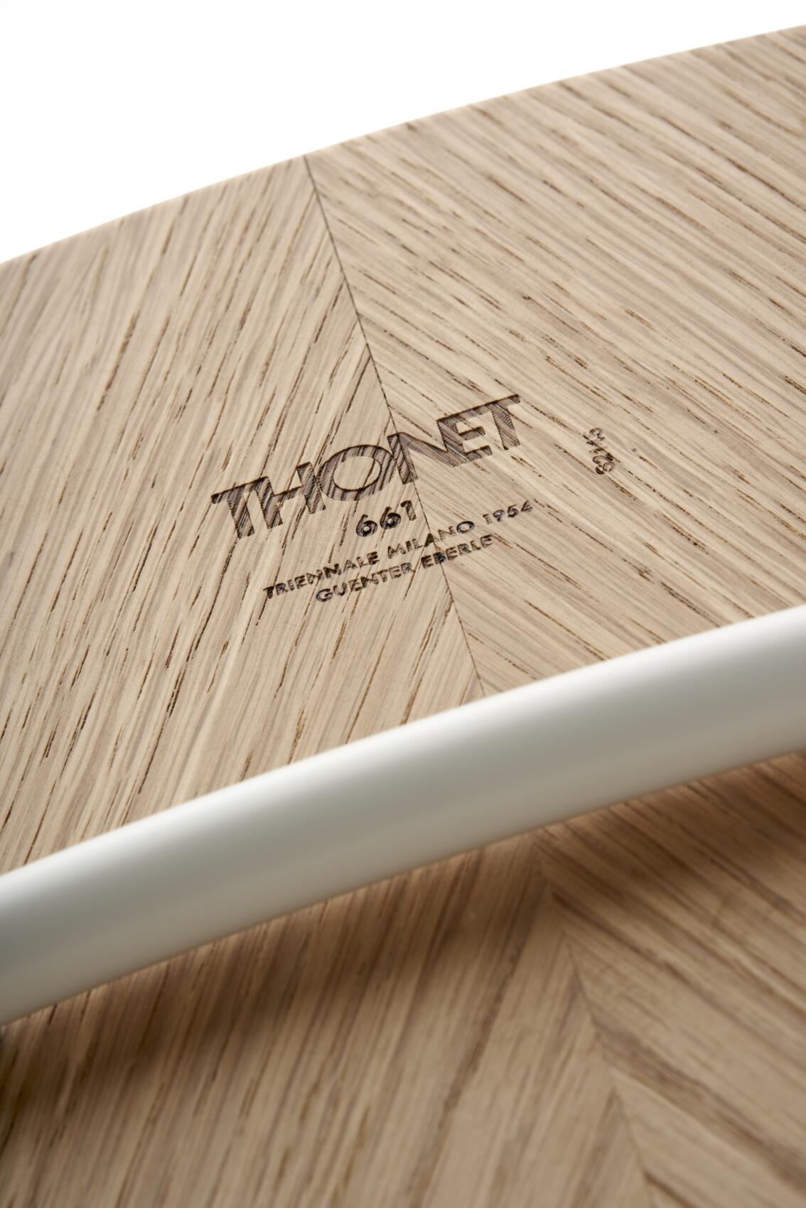 Detailaufnahme der Holzoberfläche des Thonet S 661 Stahlrohrstuhls mit eingraviertem Thonet-Logo und Stahlrohr.