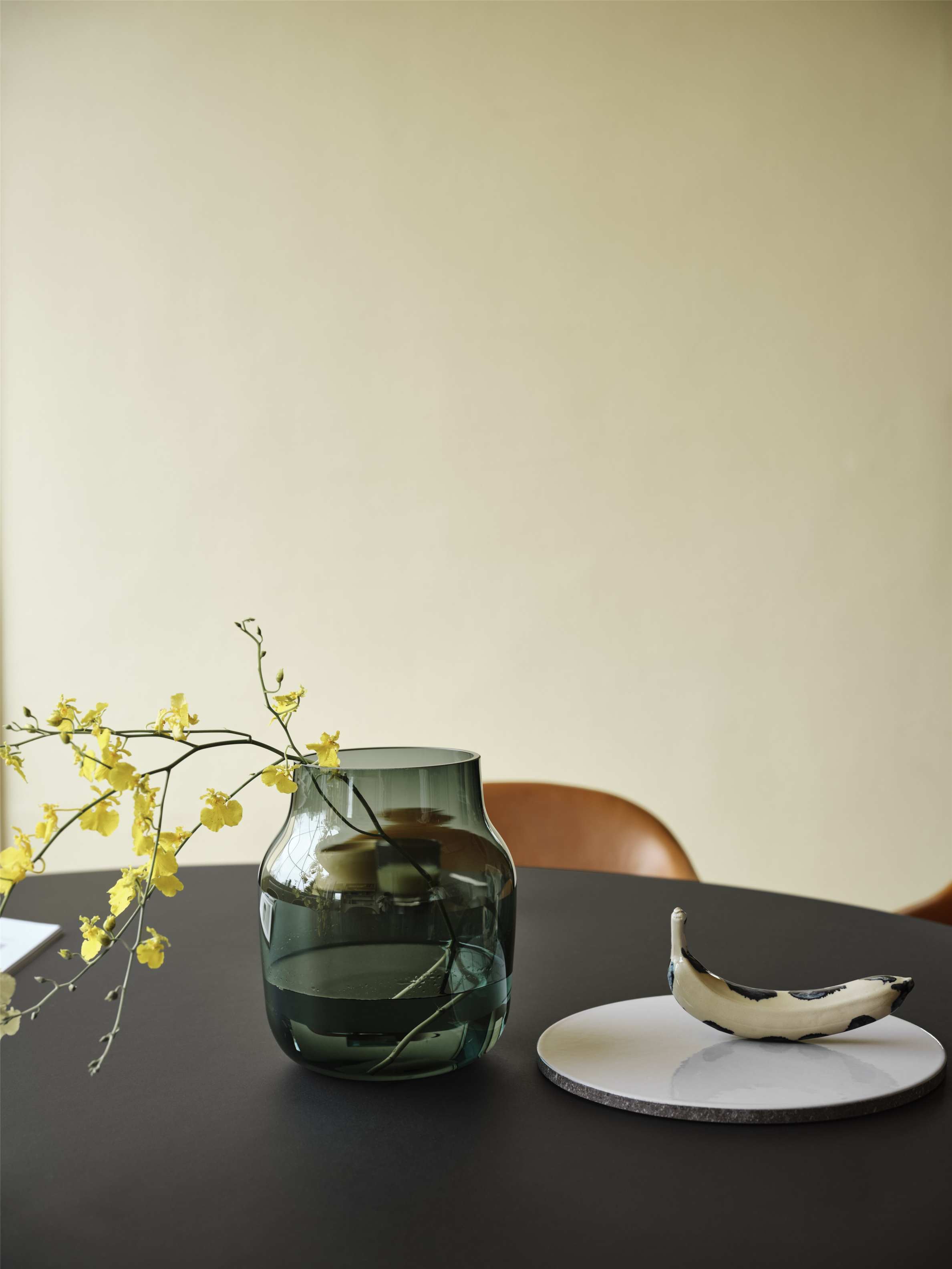 MIDST Table Esstisch von Muuto, runder Esstisch in Schwarz mit Vase und dekorativer Keramik-Banane.