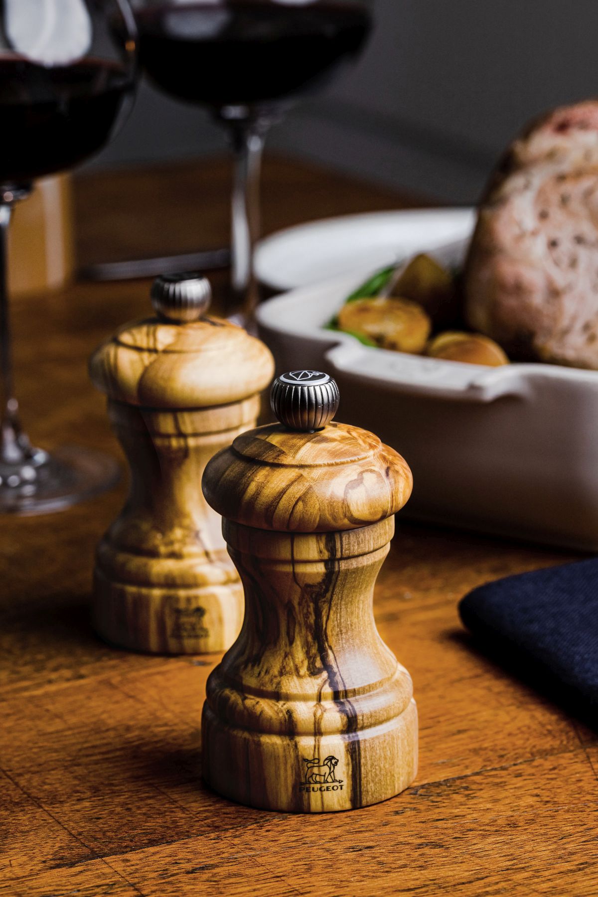 Zwei Peugeot Salz- und Pfeffermühlen aus Olivenholz, 10 cm, auf einem Holztisch.