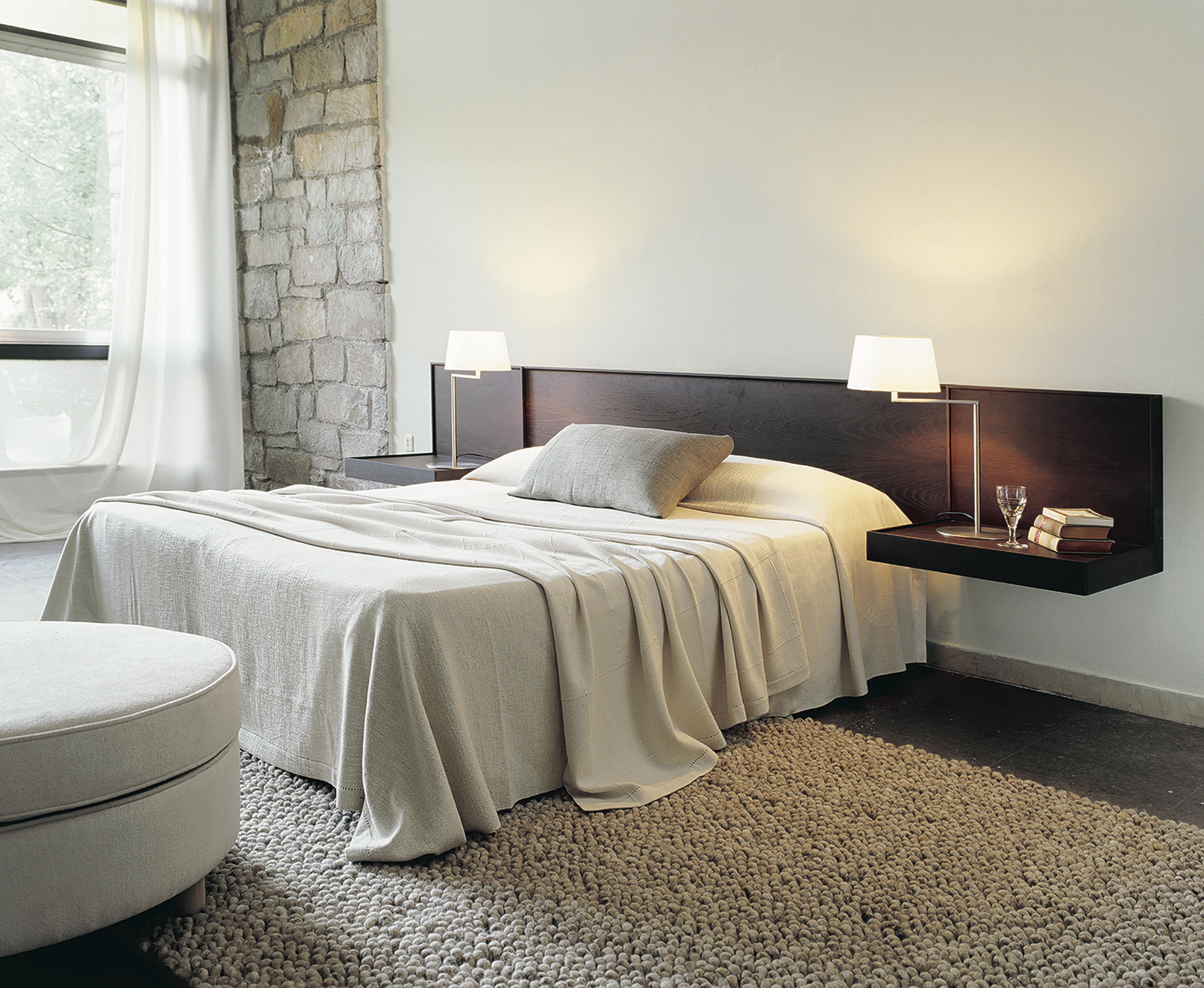 Schlafzimmer Interieur mit Bett, Teppich und Americana Tischleuchte von Santa & Cole auf einem Nachttisch.