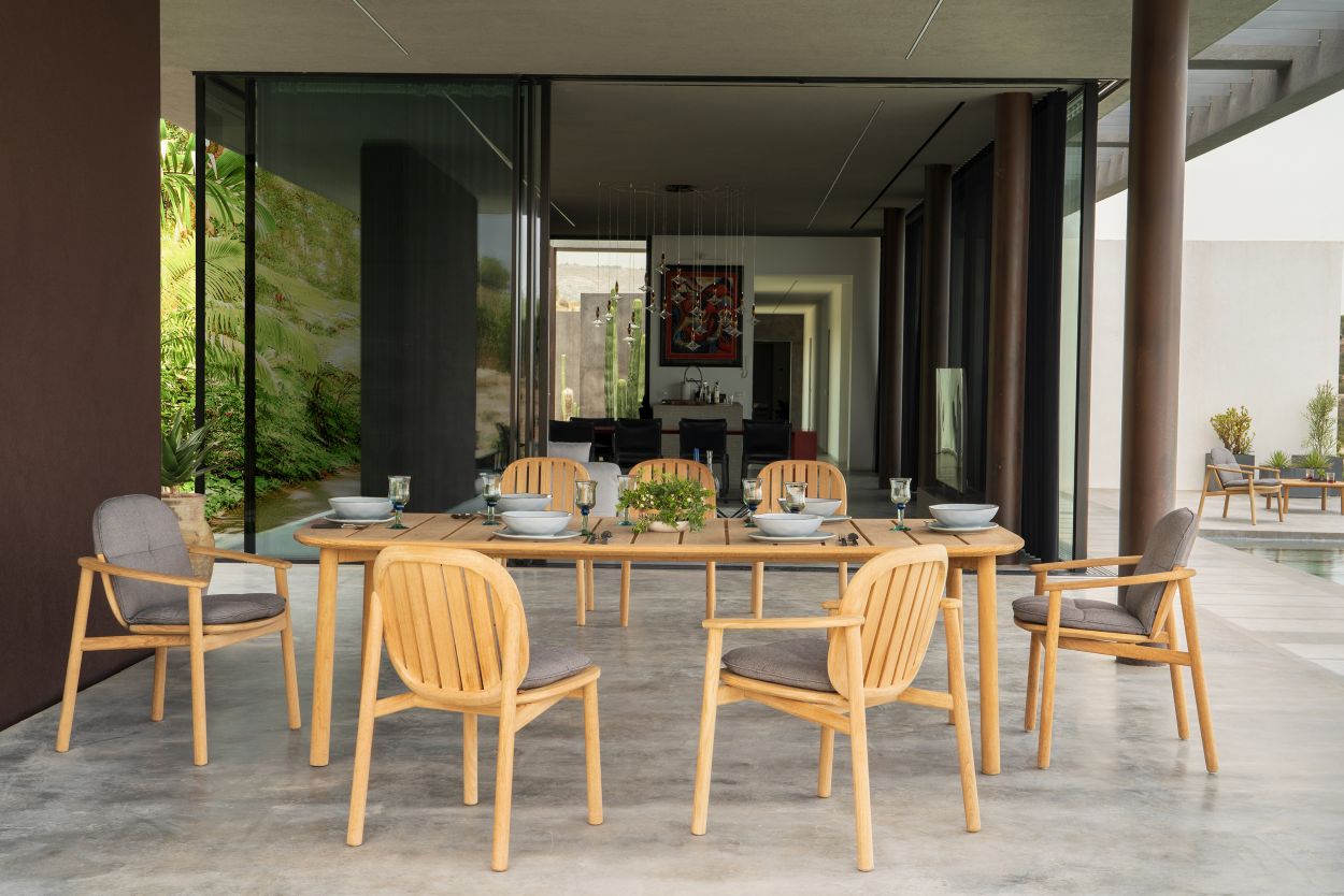 Emu Twins Stuhl Outdoor: Gartengarnitur mit Esstisch und Holzstühlen mit grauen Sitzkissen auf Terrasse.