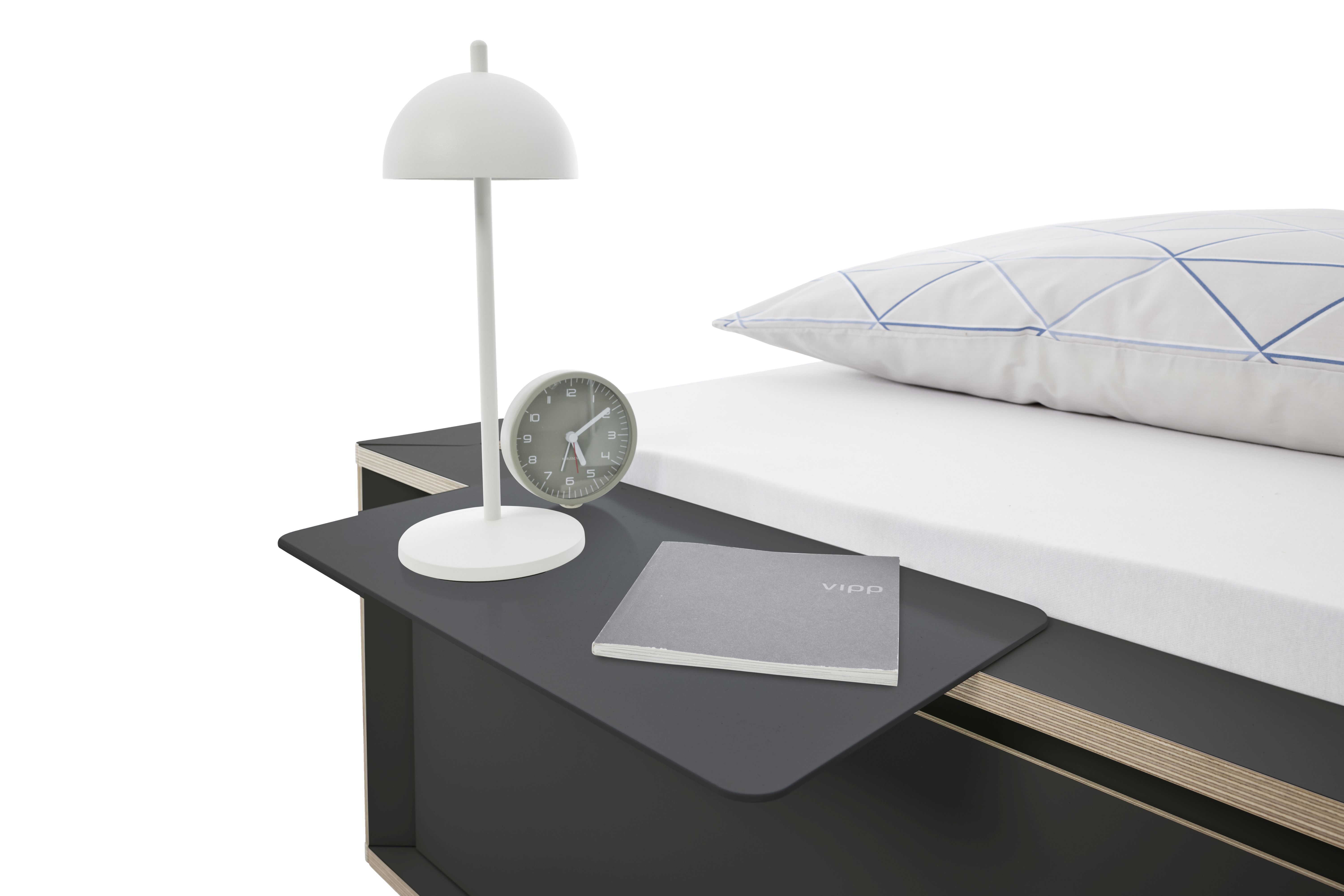 Spaze Bett von Müller Möbelwerkstätten mit Nachttisch, Lampe, Uhr und Kissen im Schlafzimmer.