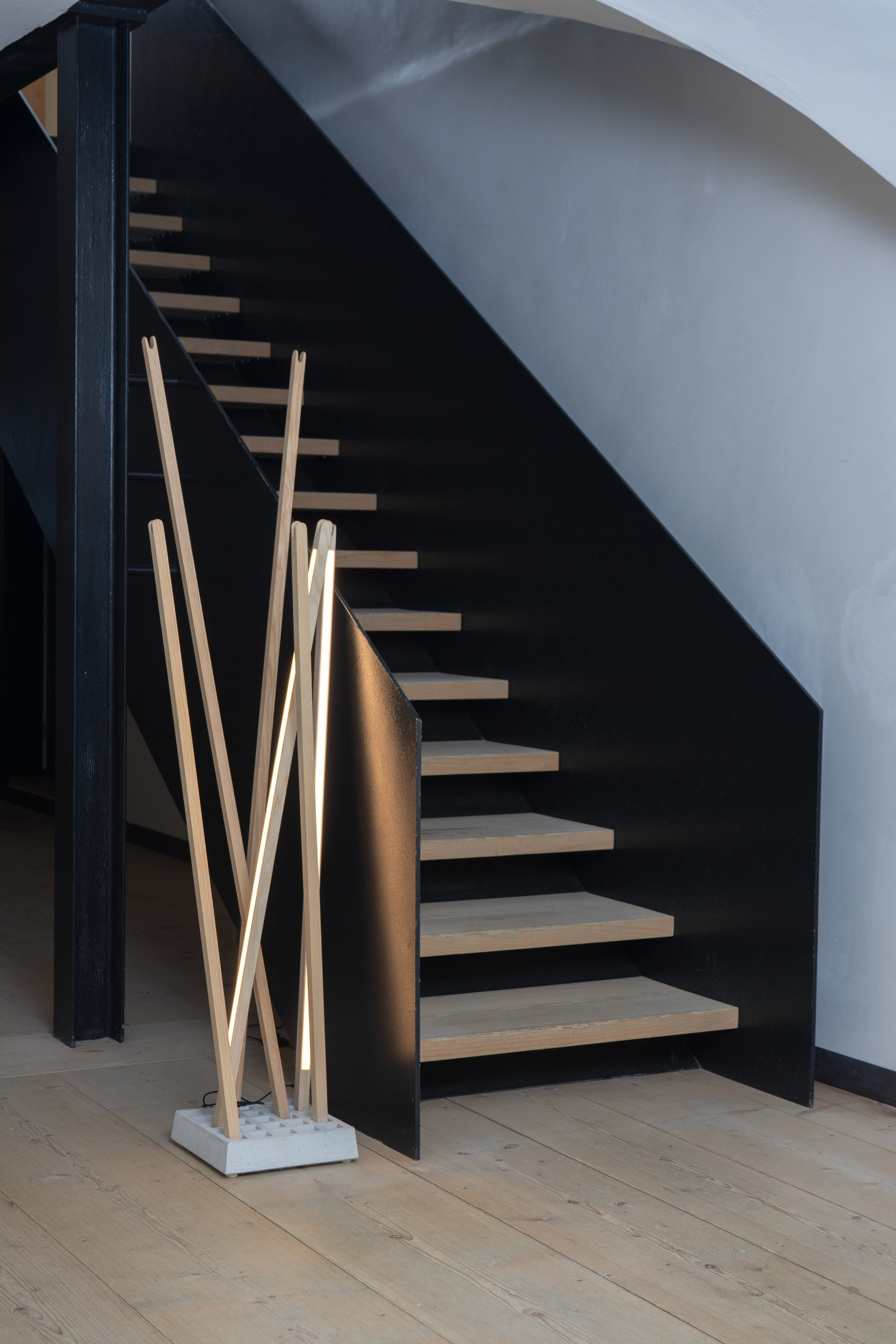 Nils Holger Moormann Pin Light Leuchte aus Holz und Beton vor Treppe.