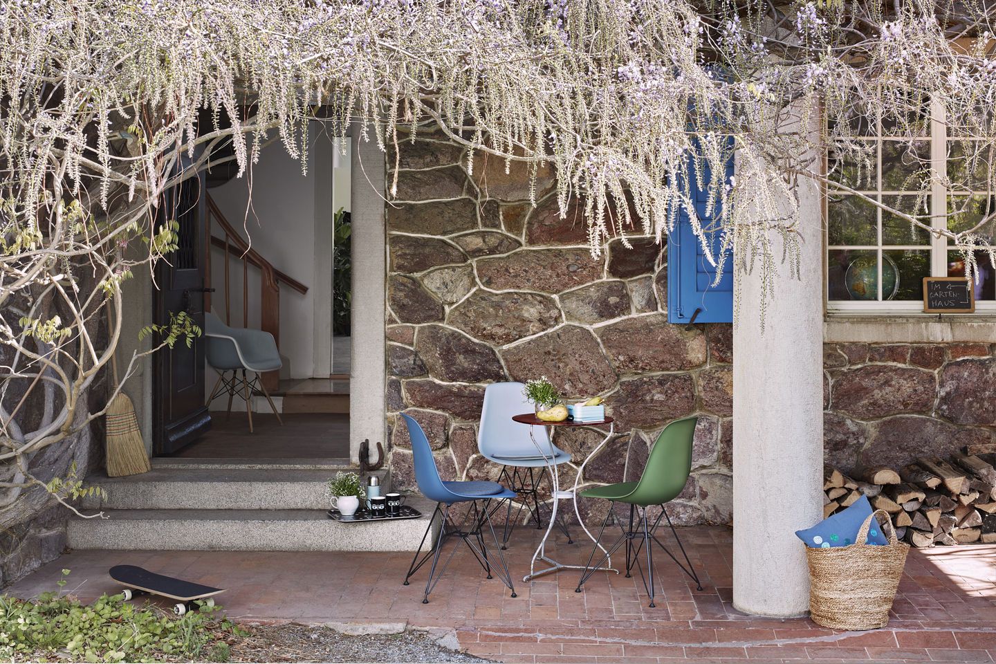 Drei Eames DSR Stühle mit Sitzpolster von Vitra auf einer Terrasse vor einem Haus.