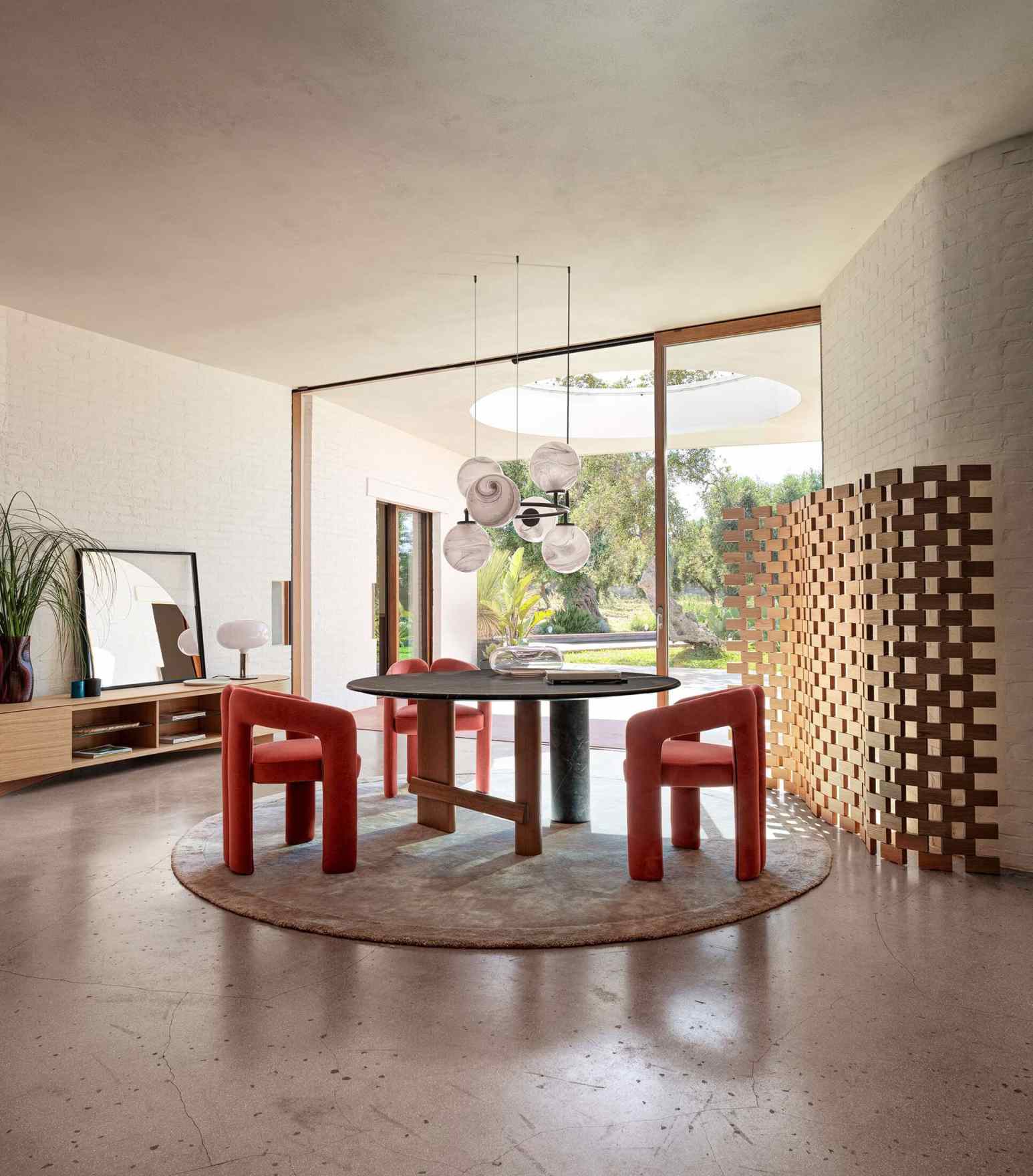 Innenaufnahme eines Esszimmers mit Cassina 562 Dudet Sessel in Orange um einen runden Tisch.
