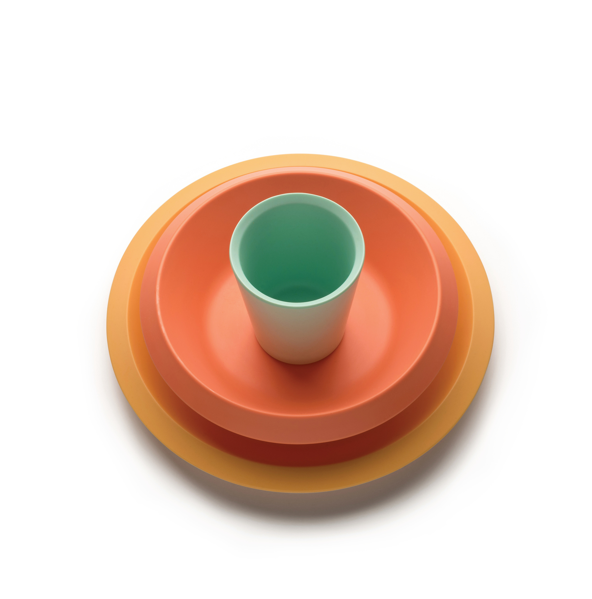 Alessi Kindergeschirr Set: Teller, Schüssel und Becher in Orange und Grün.