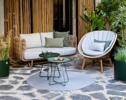 Gartenmöbel Set aus Rattan: Sofa, Sessel, Beistelltische und Teppich für den Außenbereich.