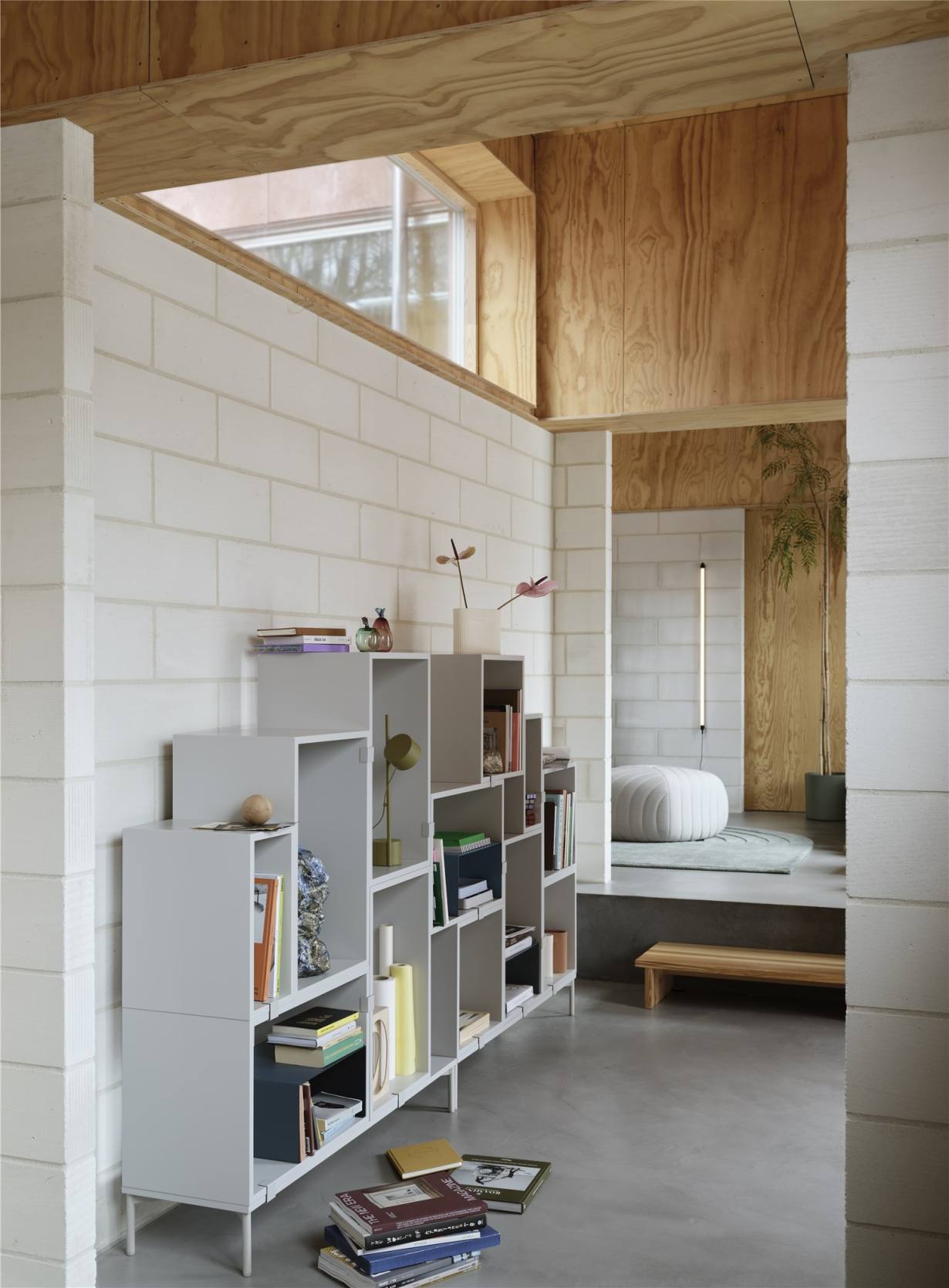 Innenaufnahme mit Bücherregal und der Post Table Tischleuchte Muuto in Braun-Grün.