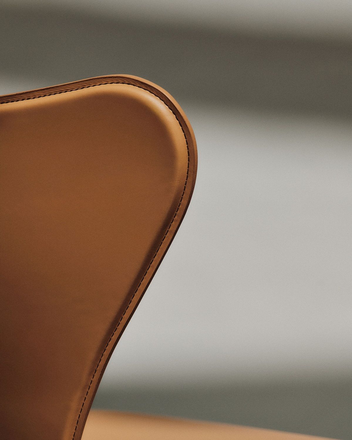 Detailaufnahme der Rückenlehne des Fritz Hansen Siebener Stuhls mit braunem Lederbezug und feinen Ziernähten.