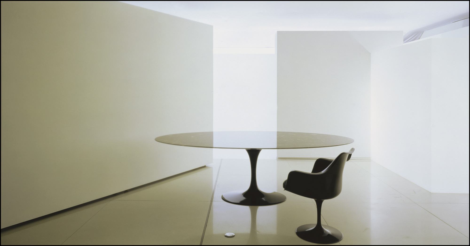 Saarinen Esstisch rund von Knoll International mit schwarzer Tischplatte und passendem Tulpenfuß-Stuhl in minimalistischem Raum.