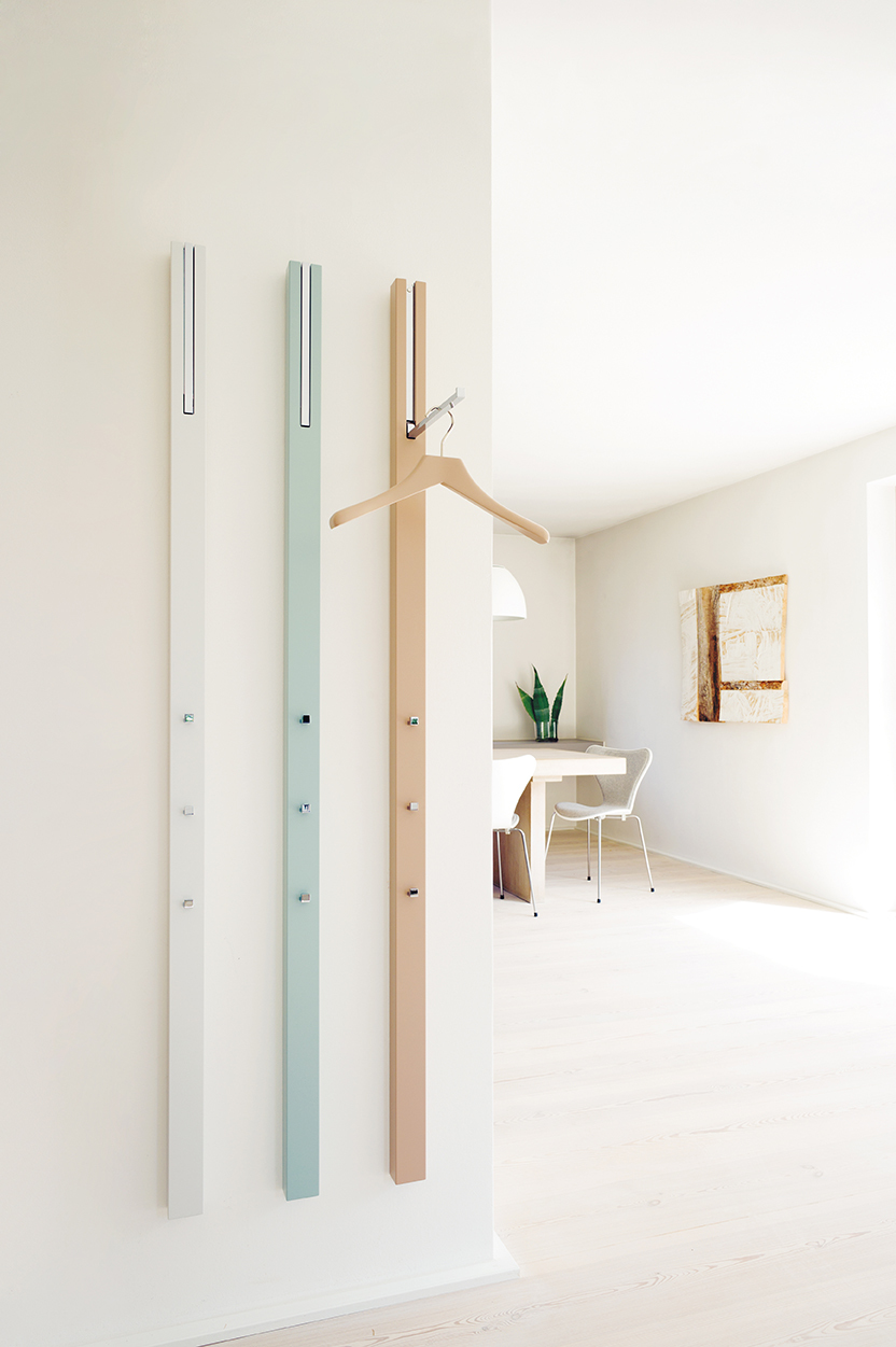 Drei farbige Line Garderobenelemente von Schönbuch an einer weißen Wand, minimalistisches Design mit Kleiderhaken.