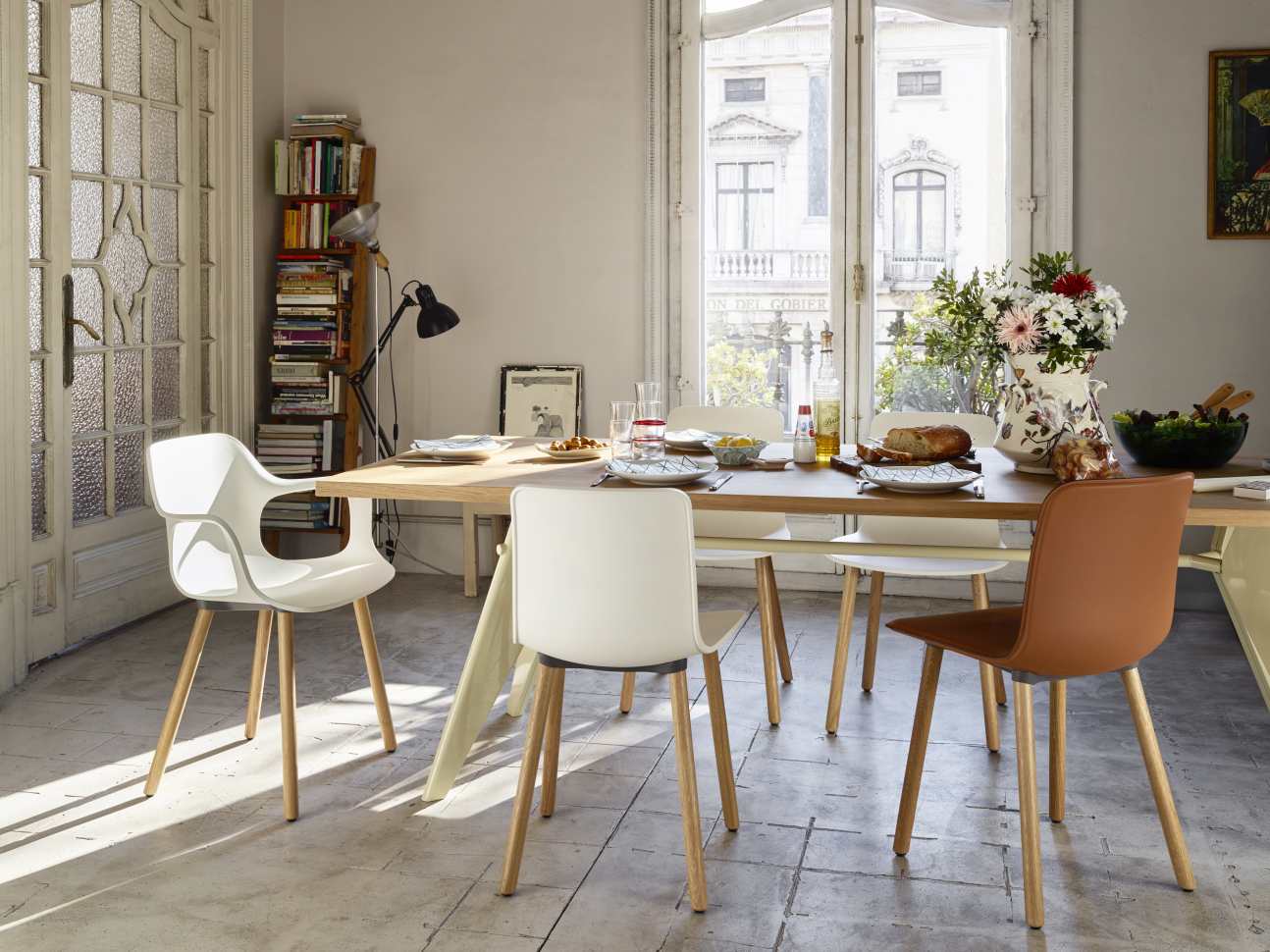 Vitra EM Table Holztisch mit Stühlen in hellem Esszimmer mit großem Fenster und Dekoration.