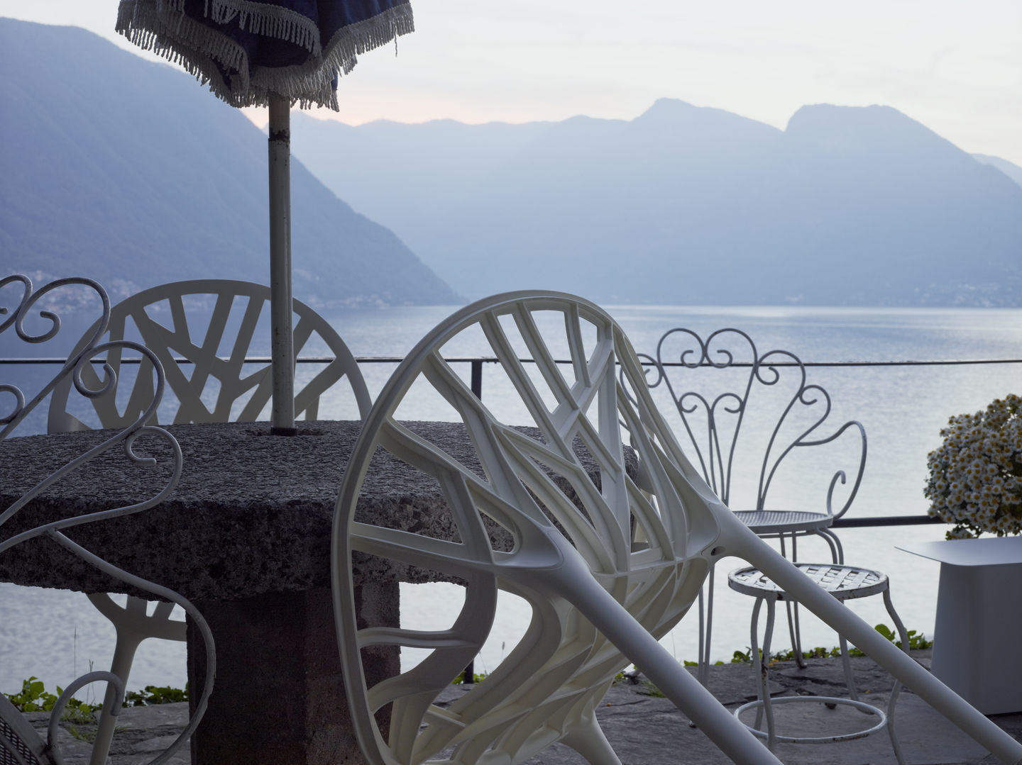 Nahaufnahme eines kleinen, weißen Vitra Metal Side Table Beistelltisches im Freien mit Seeblick.