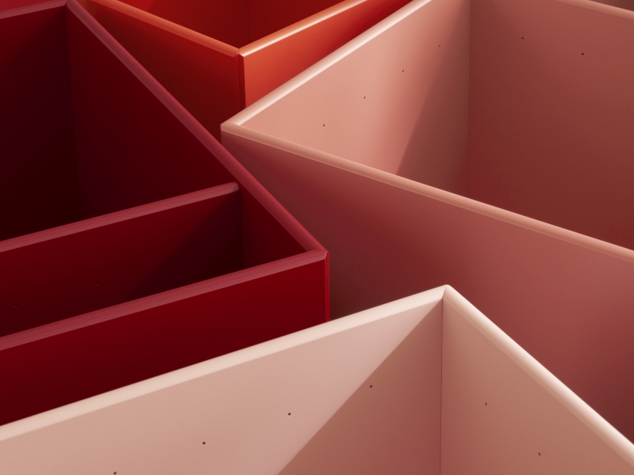 Detailaufnahme von Colour Box Aufbewahrungsboxen in Rot- und Rosatönen, modulare Regale für Ordnung.