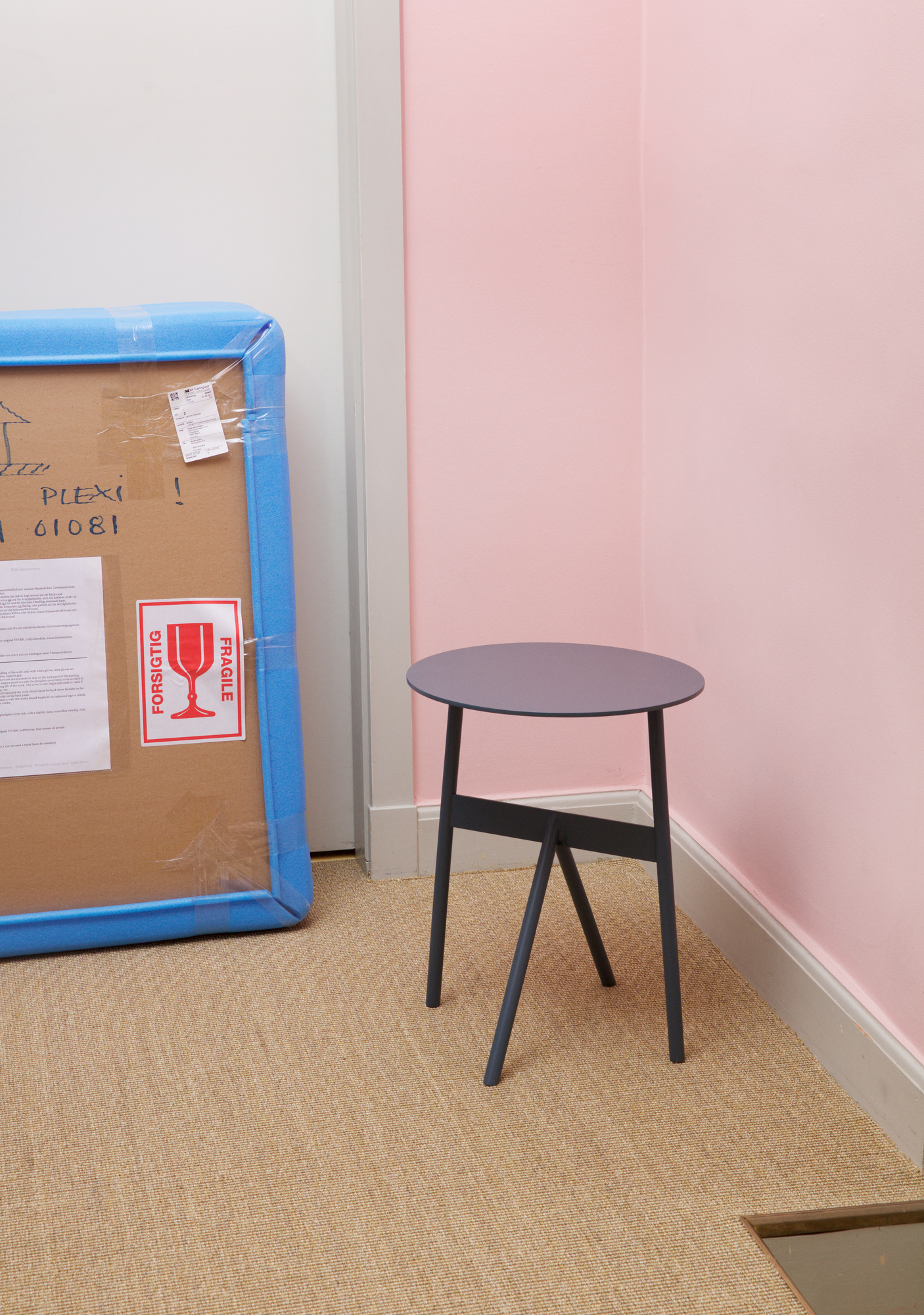 Normann Copenhagen Stock Table Beistelltisch in Grau vor rosa Wand und verpackter Lieferung. Moderner kleiner Tisch.