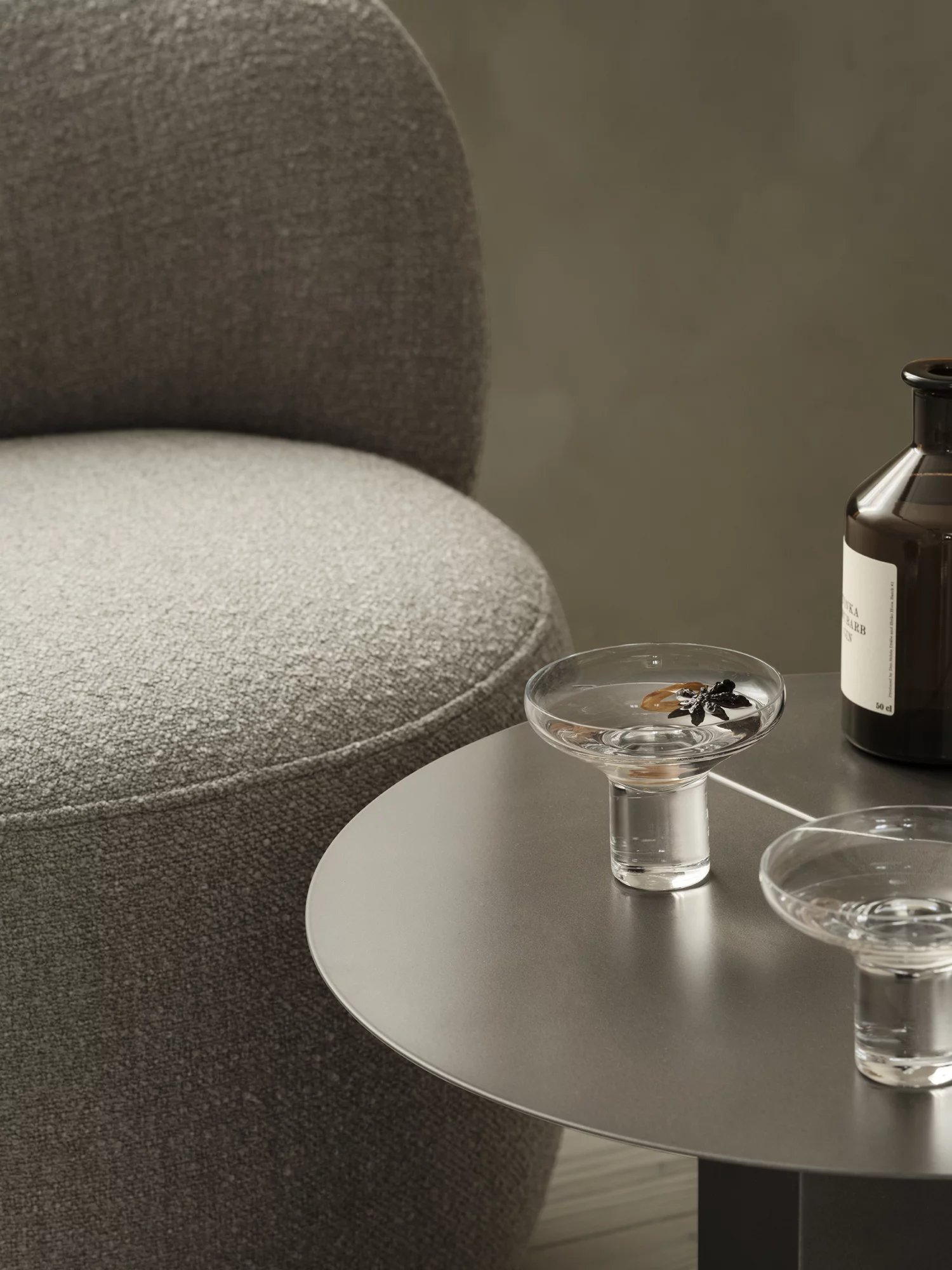 Oru Beistelltisch von Blomus in Burned Metal mit Getränken und Flasche auf einer Couch.