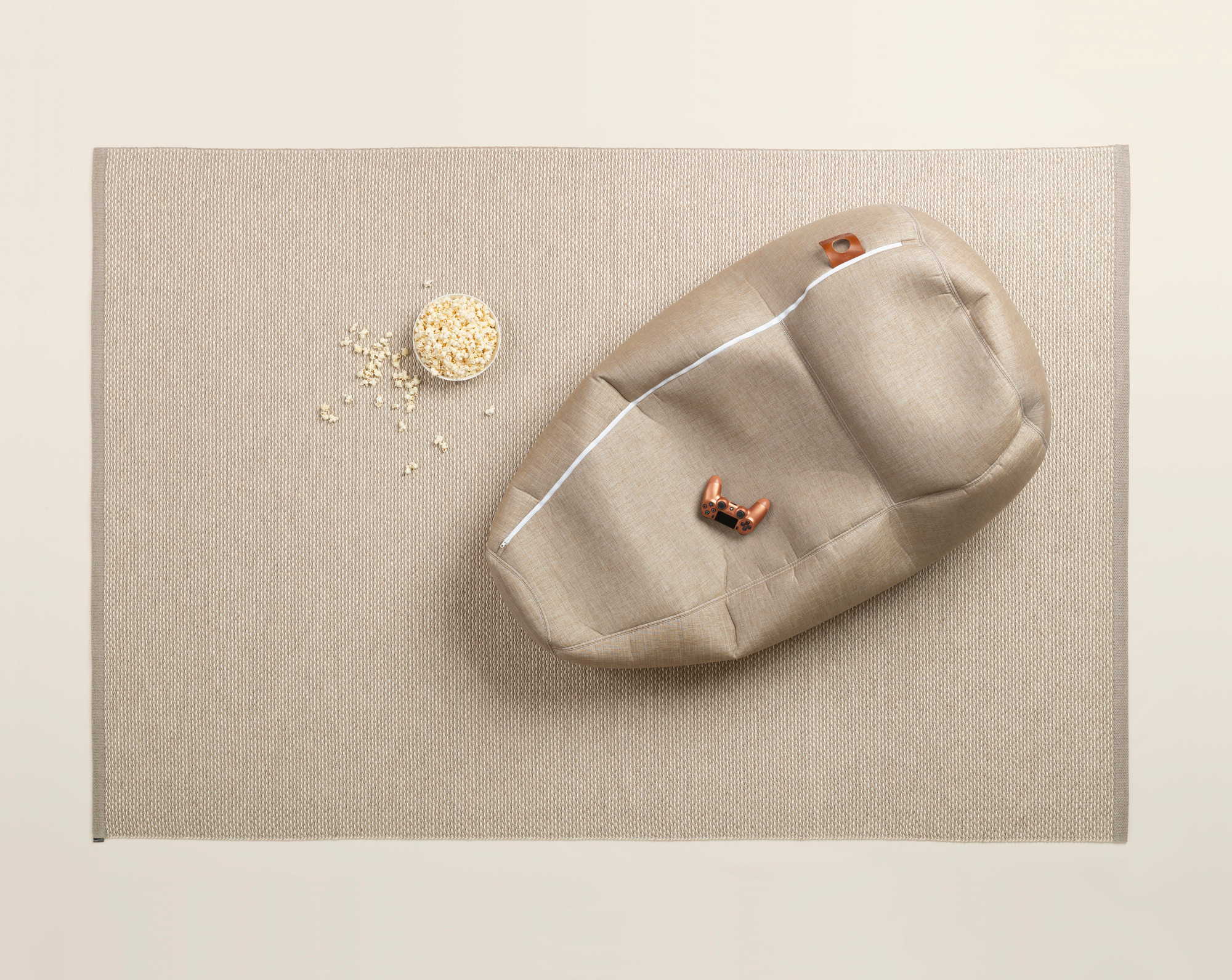 Effi Kunststoffteppich von Pappelina, 180x260 cm, in Beige mit Sitzsack und Popcorn. Outdoor Teppich.