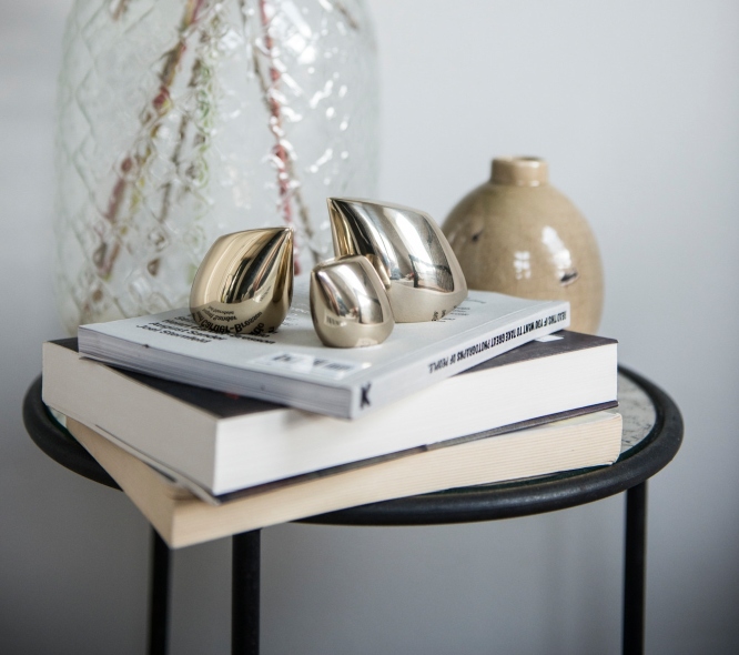 Goldene Deko-Objekte, Skulpturen auf Büchern auf einem Beistelltisch, moderne Wohnaccessoires für stilvolle Dekoration.