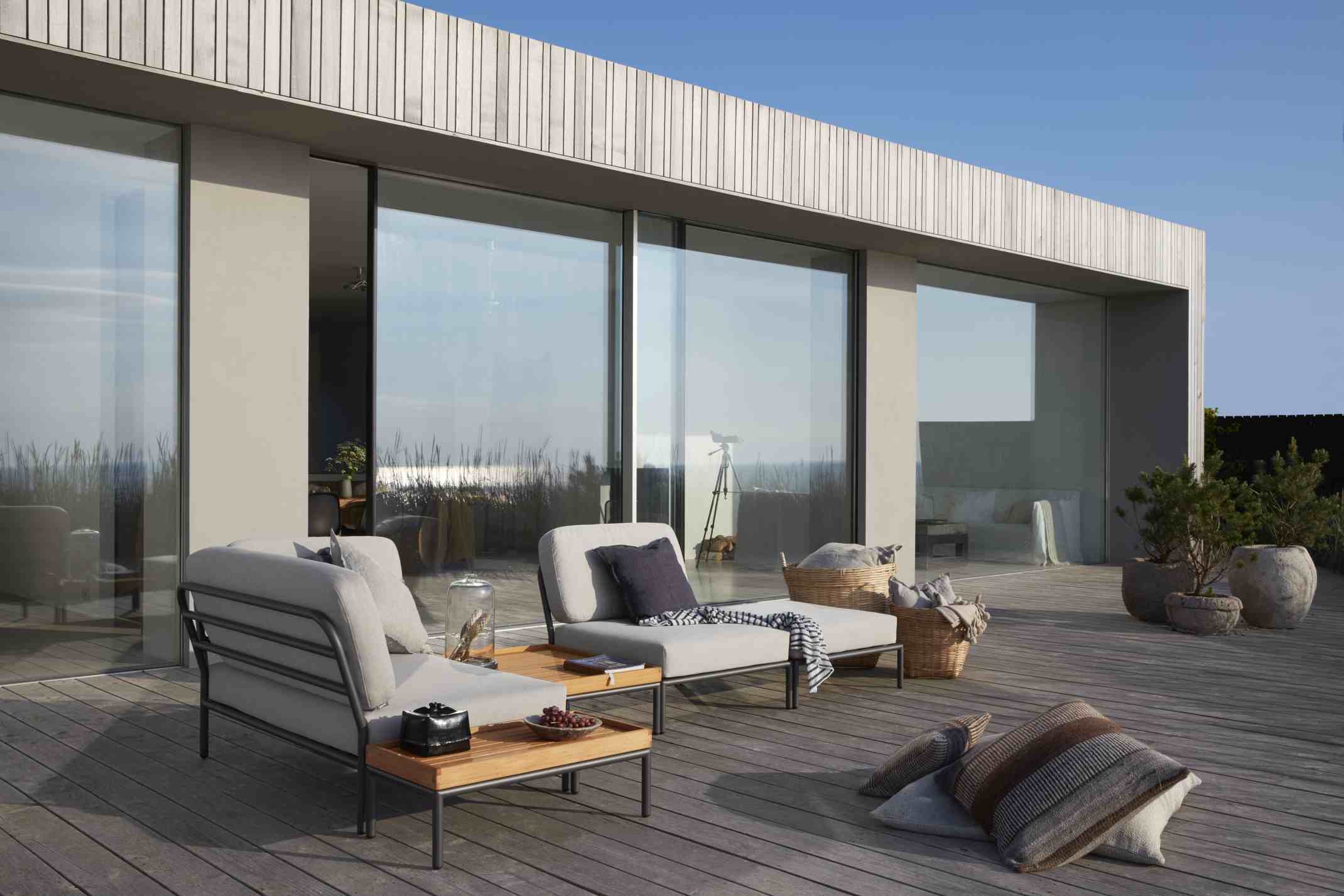Houe Level Couchtisch auf Holzterrasse mit Loungemöbeln und Kissen für entspannte Outdoor-Momente.
