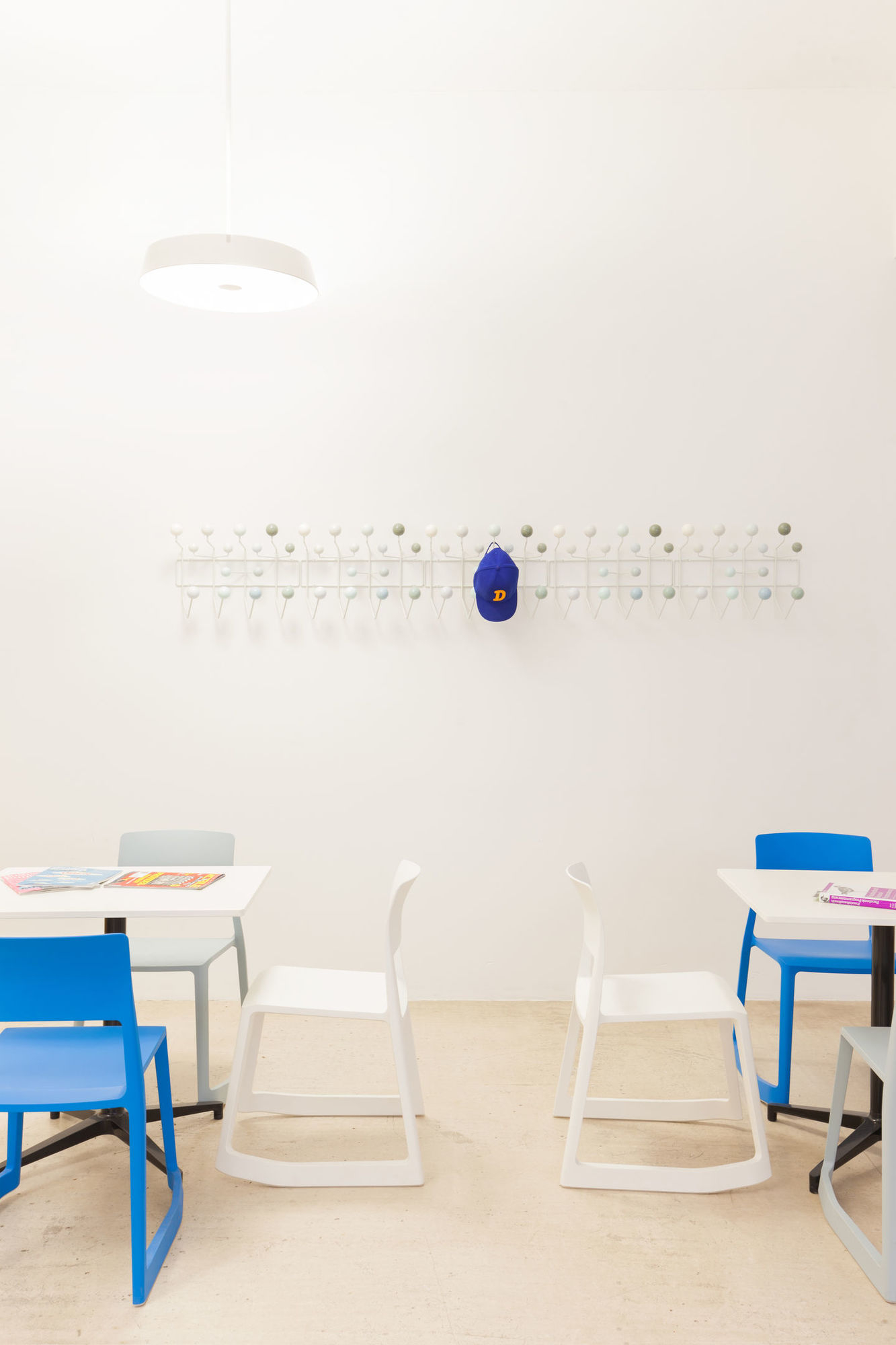 Helle, freundliche Raumszene mit weißen und blauen Tip Ton RE Stühlen von Vitra an Tischen.