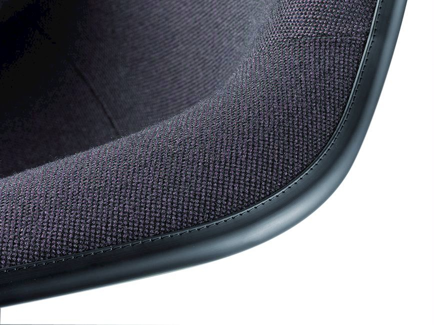 Detailaufnahme des Eames Plastic Arm Chair DAL Stuhls von Vitra, vollgepolstert mit schwarzem Stoffbezug.