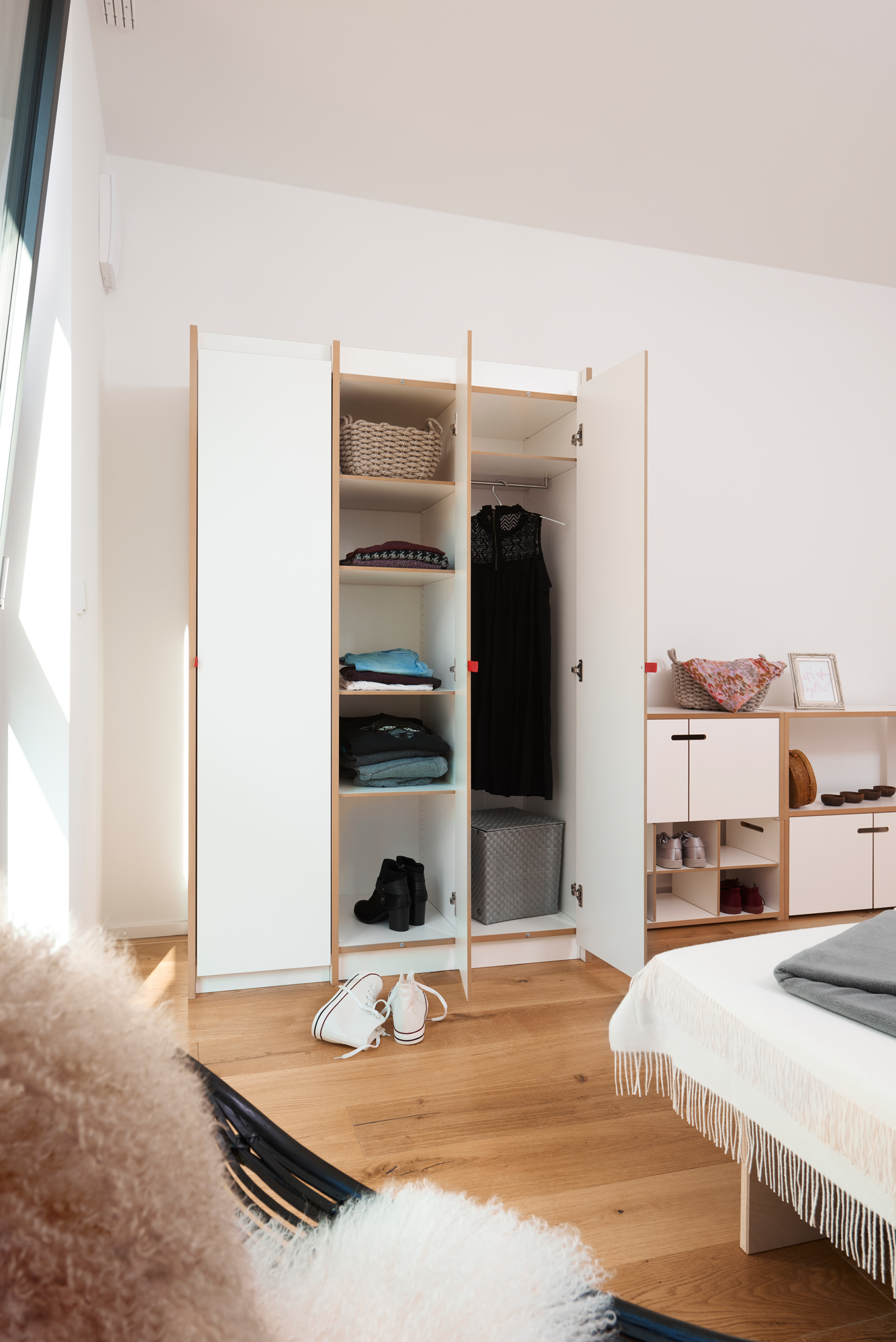 Tojo Steh Schrank Anbaumodul im Schlafzimmer mit Kleidung, Schuhen und Dekoration in offenen Fächern.