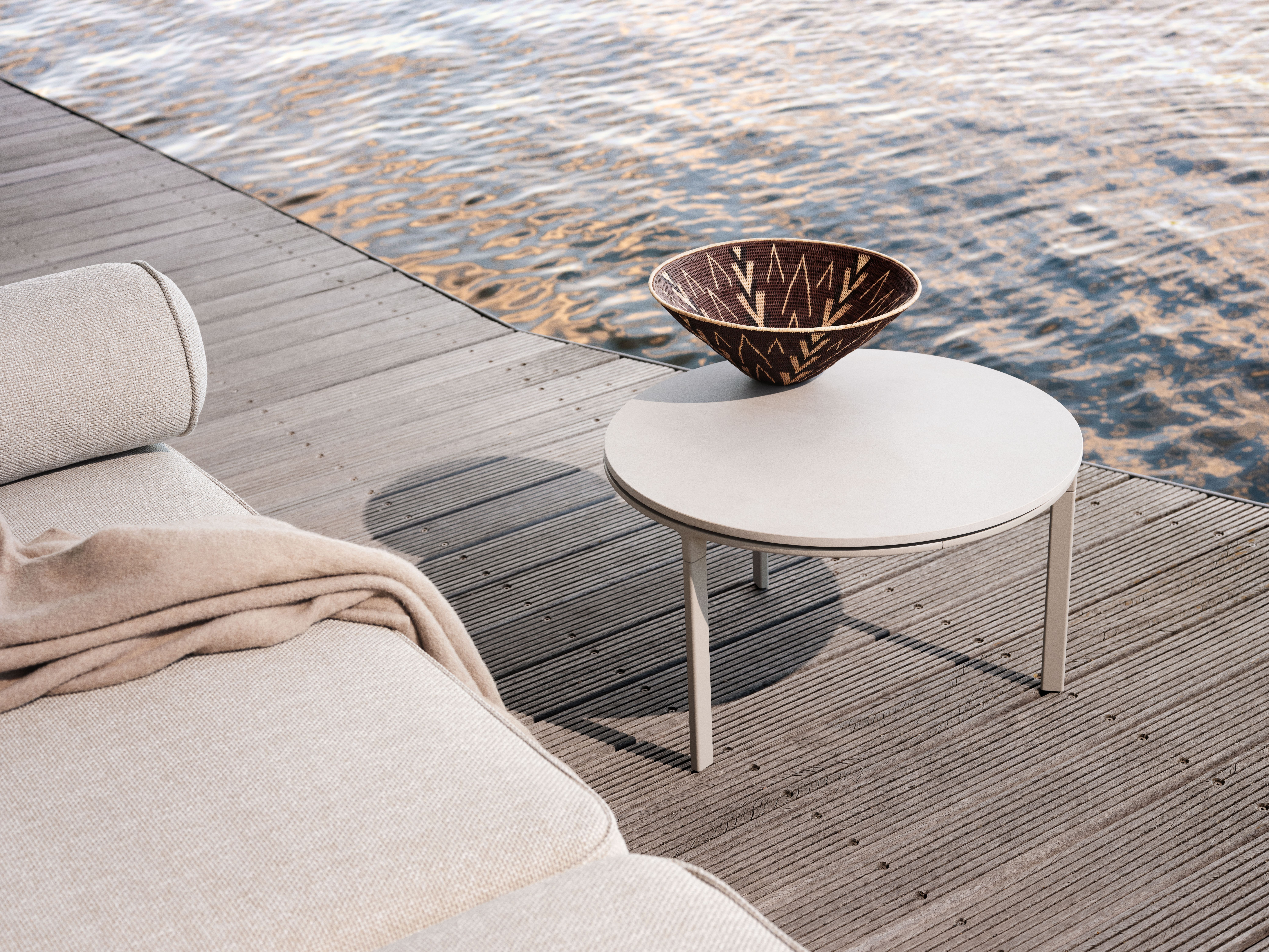 Detailaufnahme des Vipp Open-Air Outdoor Sofas mit Beistelltisch und Dekoschale auf einer Holzterrasse am Wasser.