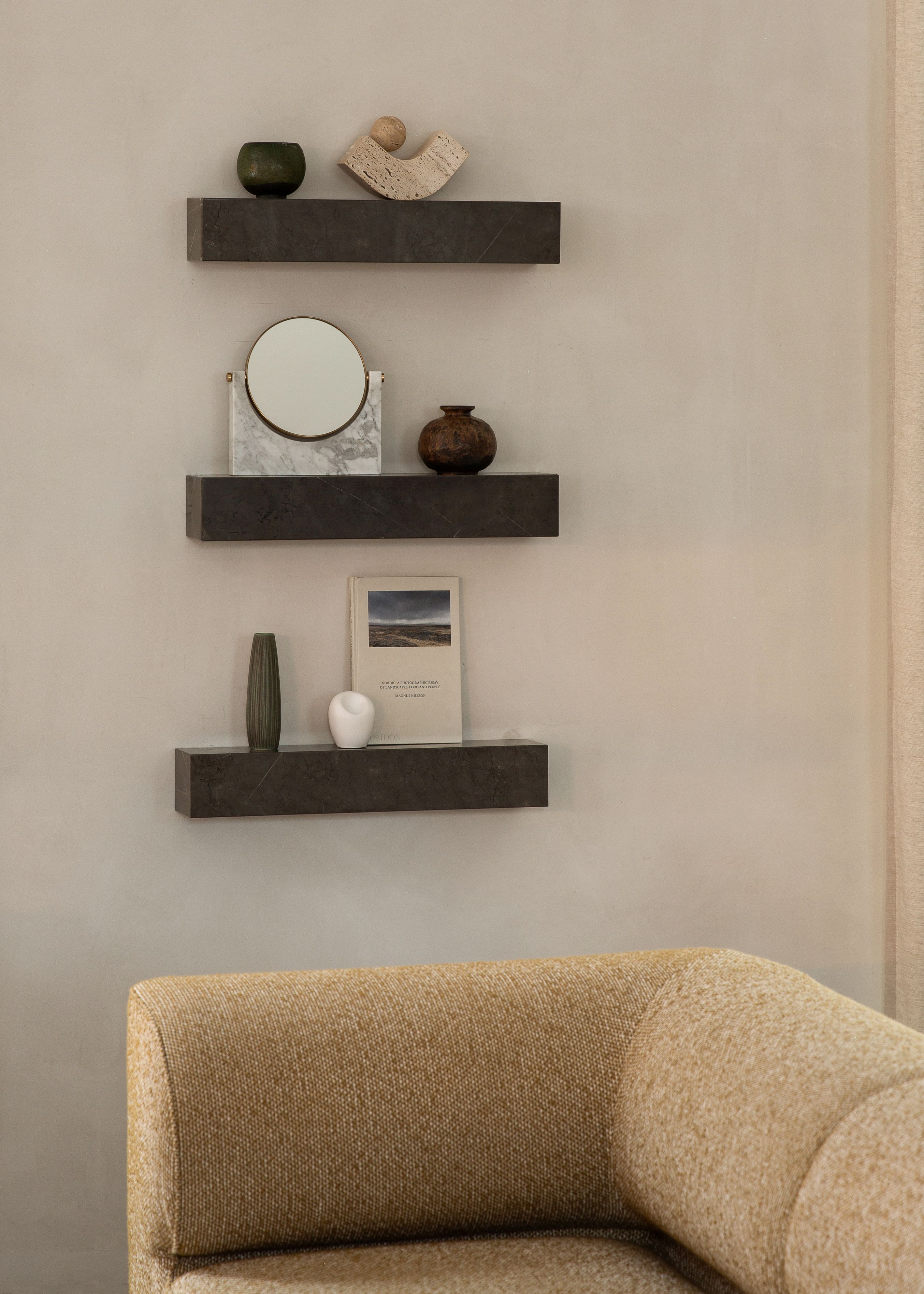 Audo Copenhagen Plinth Shelf Regale in dunklem Marmor an einer Wand mit Deko-Objekten.
