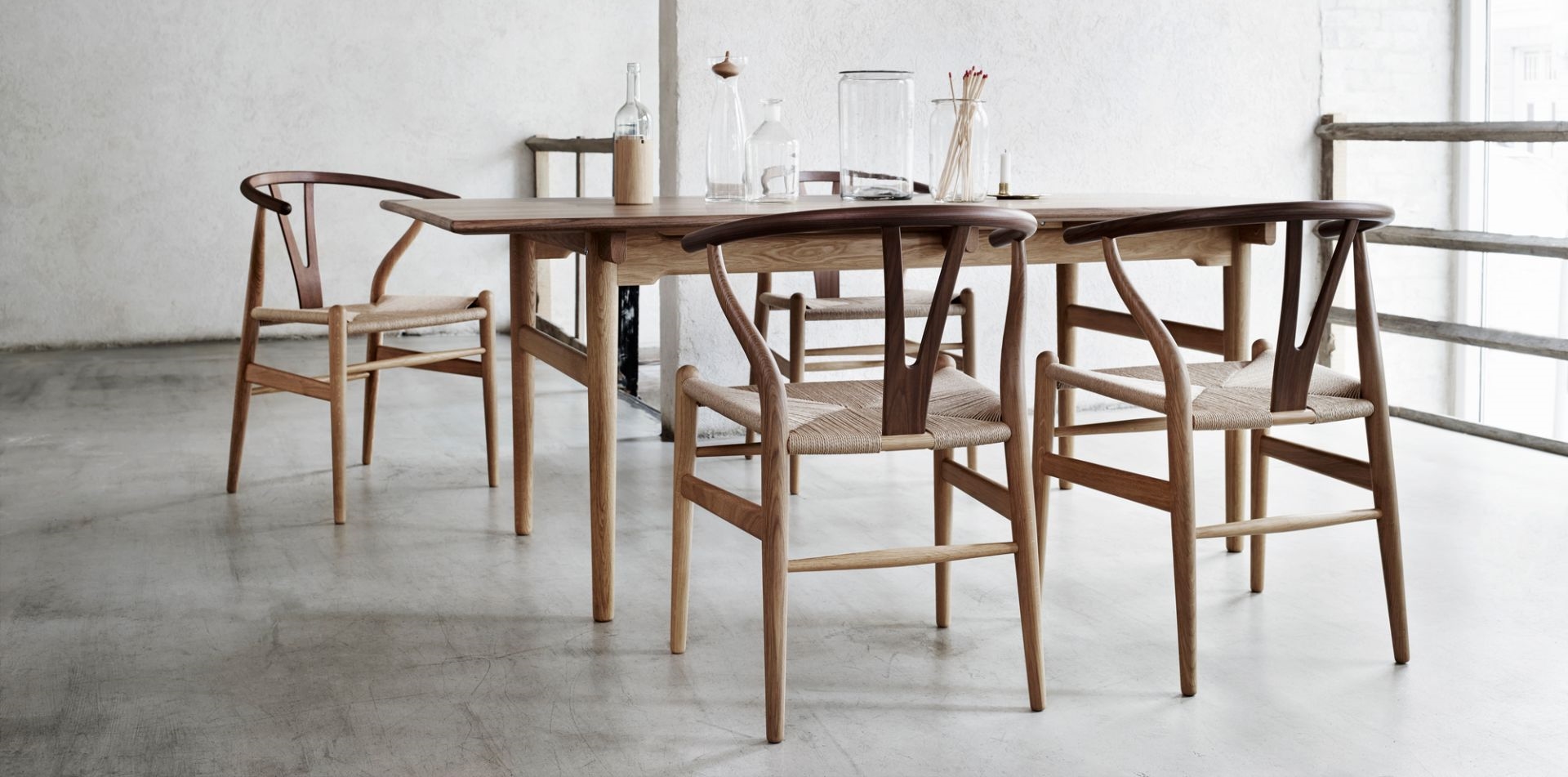 Esstisch aus Holz mit vier Wishbone Stühlen mit geflochtenen Sitzen im minimalistischen Design.