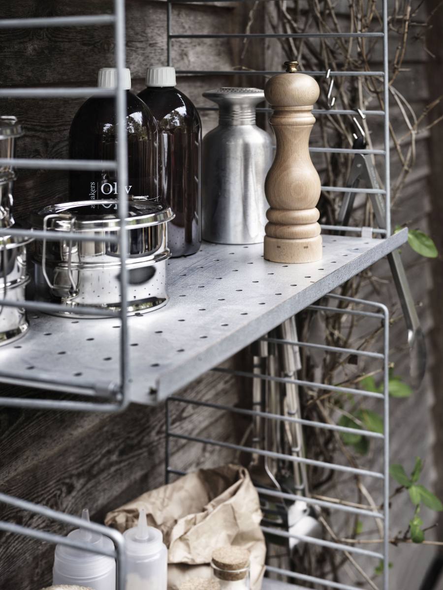 String Outdoor Regal mit Küchenutensilien und Vorräten vor einer Holzwand.