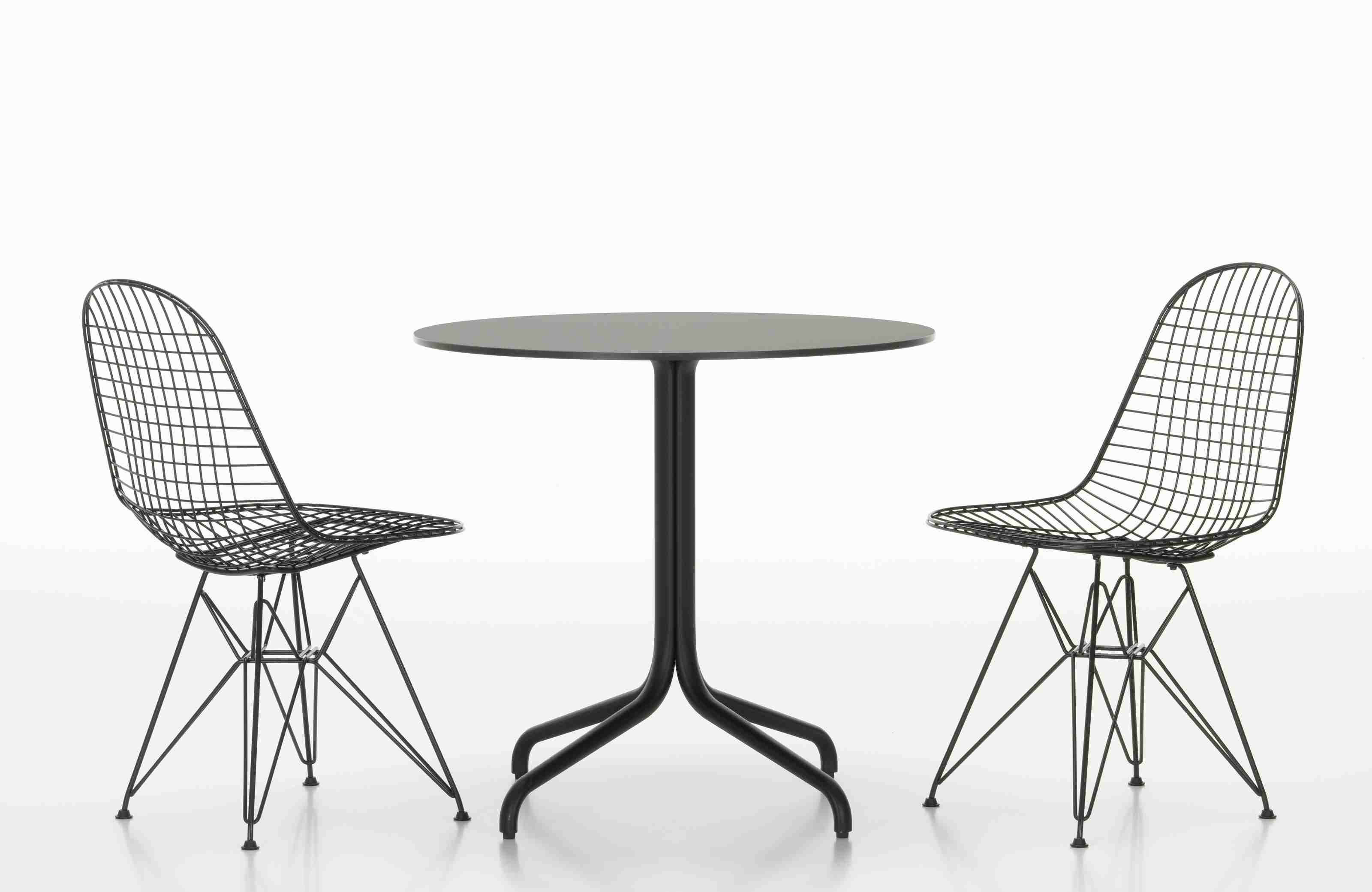 Belleville Table von Vitra mit zwei schwarzen Drahtstühlen auf weißem Hintergrund, modernes Möbeldesign.
