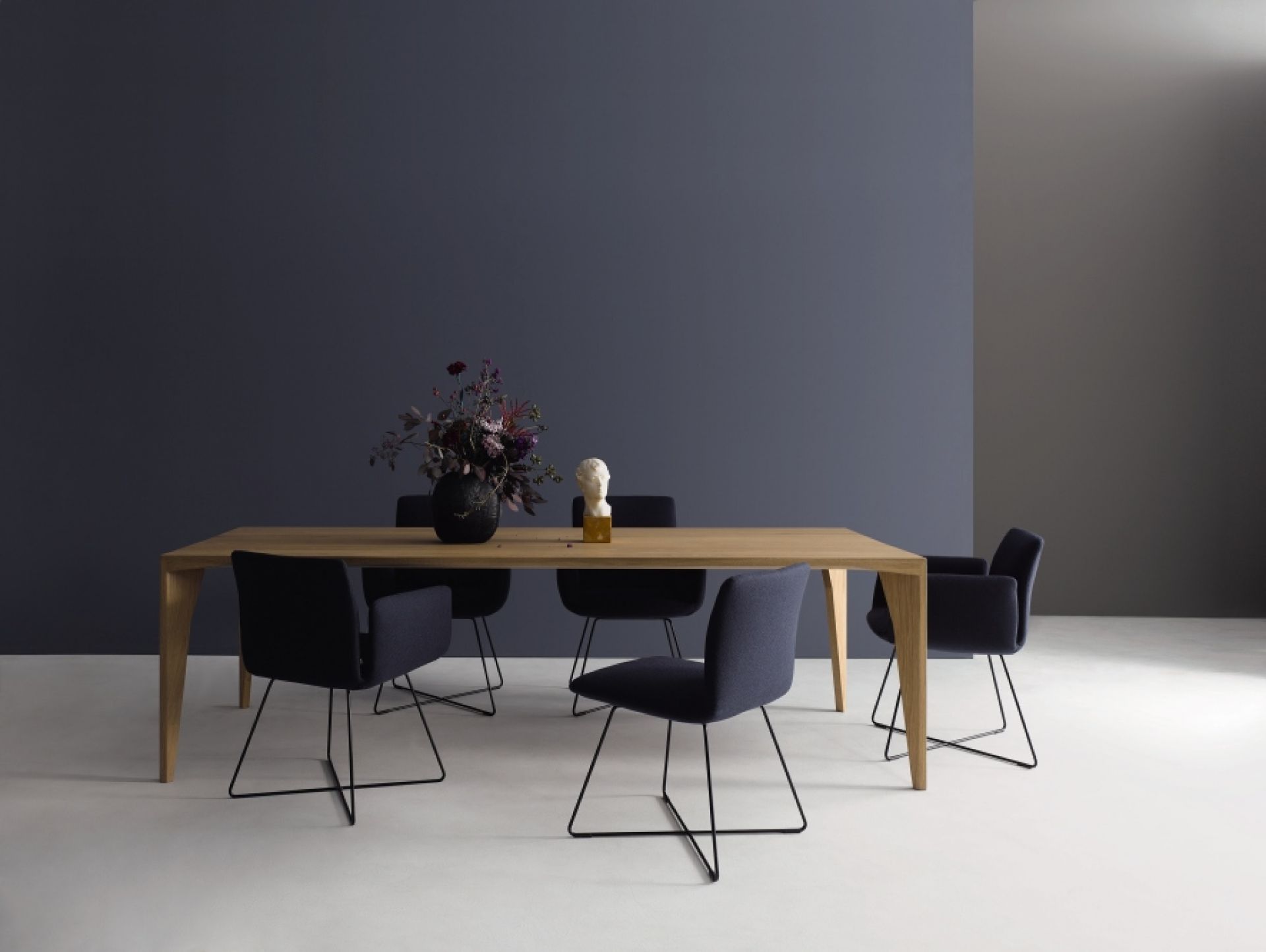 Esstisch aus hellem Holz mit sechs blauen Stühlen und Dekoration in modernem Esszimmer.