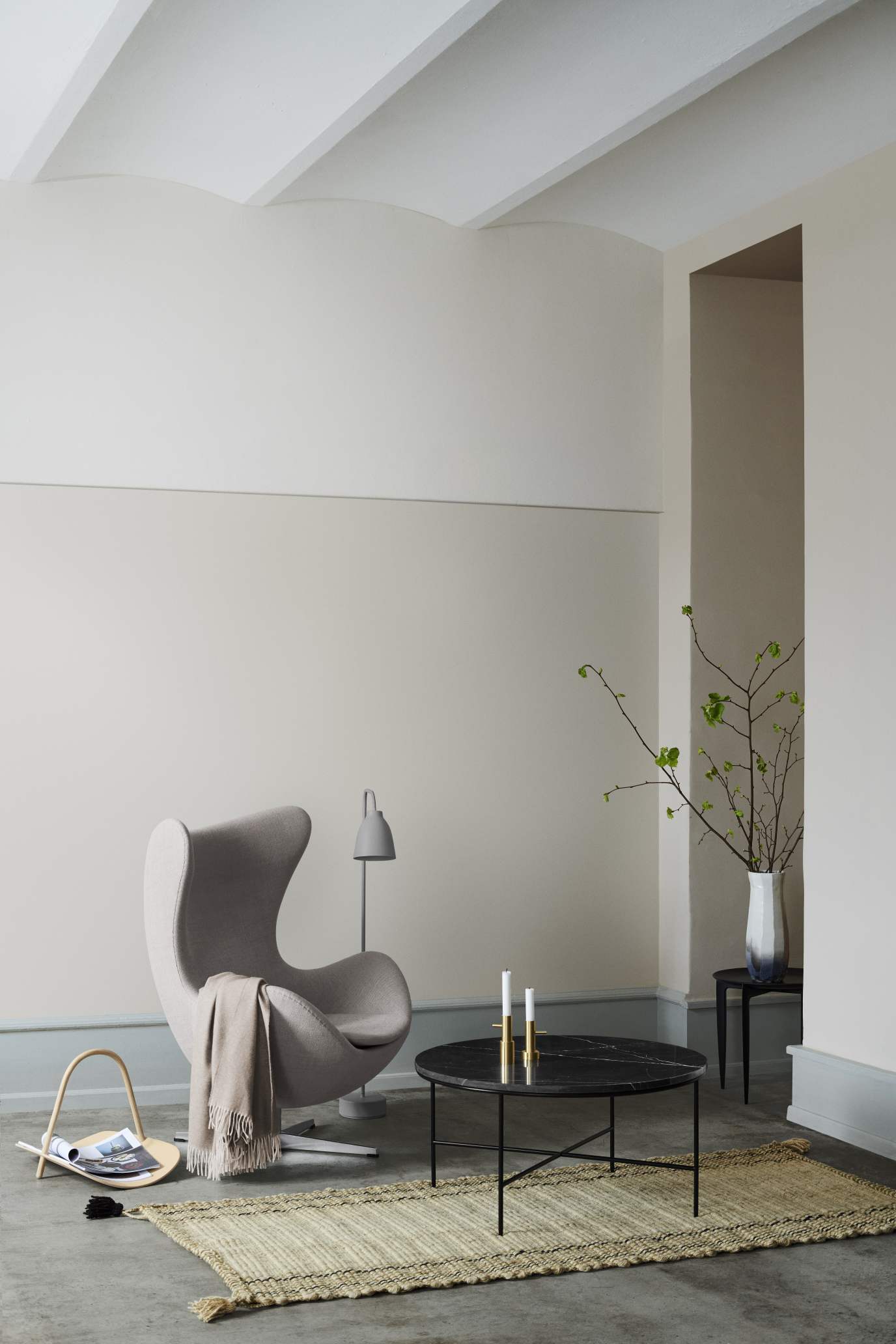 Eleganter Wohnraum mit Fritz Hansen Planner Couchtisch aus Marmor, Sessel, Teppich und Deko.