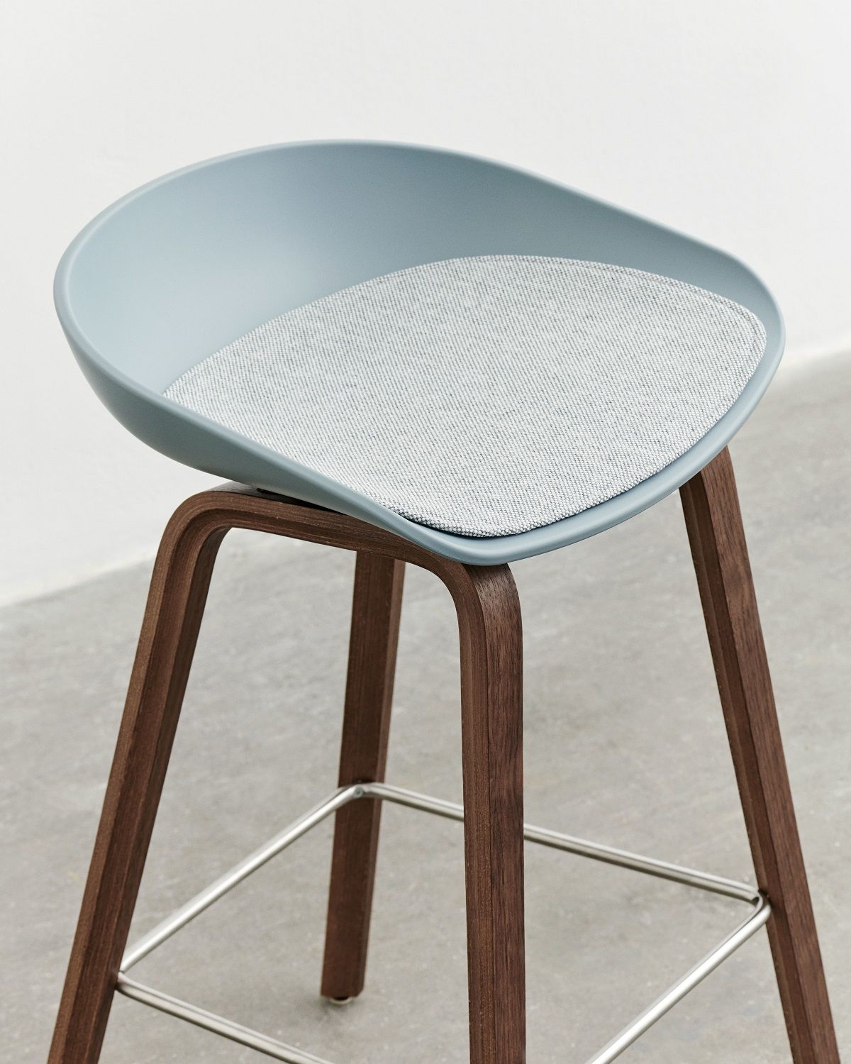 Blauer Hay Barhocker mit Holzbeinen und grauem Sitzkissen, passend für About a Stool.