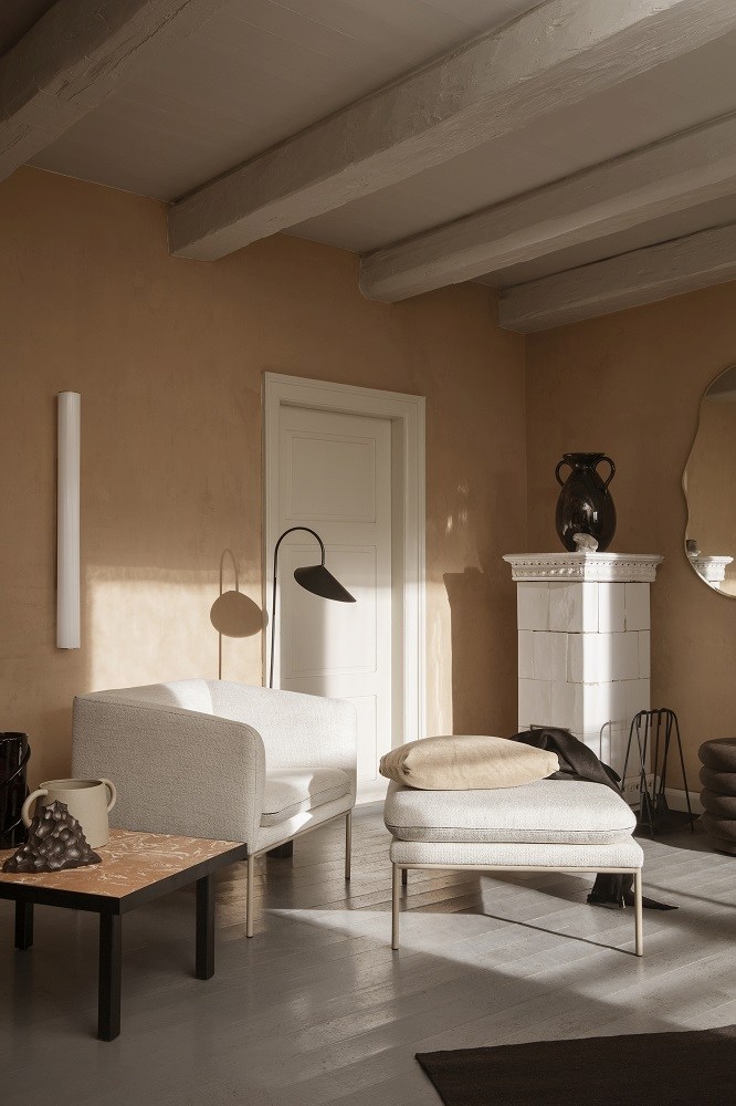 Wohnzimmer mit Arum Wandleuchte von Ferm Living, Sessel und minimalistischem Design.