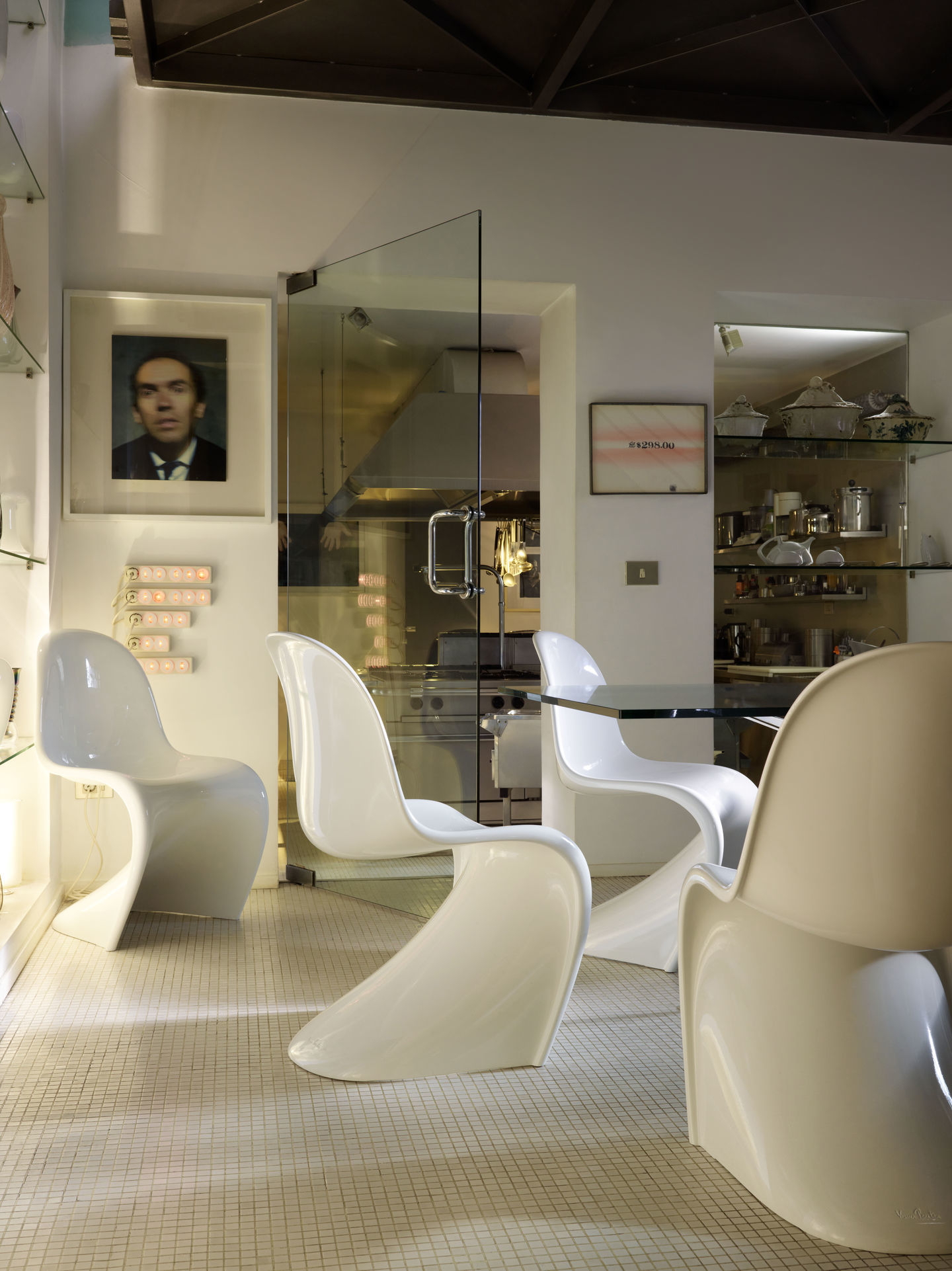 Helle Inneneinrichtung mit vier weißen Panton Stühlen von Vitra um einen Glastisch.
