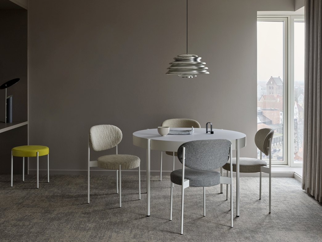 Esszimmer mit rundem Tisch, Stühlen und einem Verpan Series 430 Hocker in Gelb im Hintergrund.