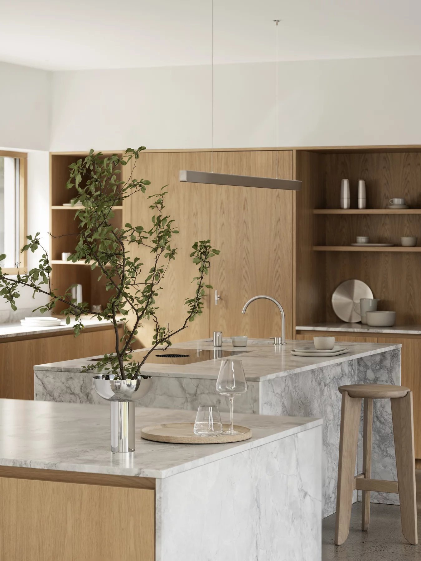 Eli Bar Stool Barhocker von Blomus in heller Küche mit Marmorinsel und Holzelementen.