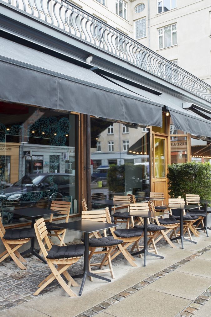 Außenbereich eines Cafés mit Vendia Chair Klappstühlen von Skagerak by Fritz Hansen und schwarzen Tischplatten.