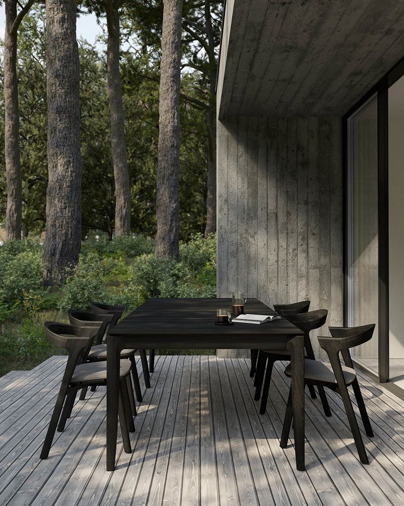 Schwarze Holz-Gartenmöbel: Esstisch mit Stühlen für den Außenbereich auf einer Holzterrasse im Grünen.