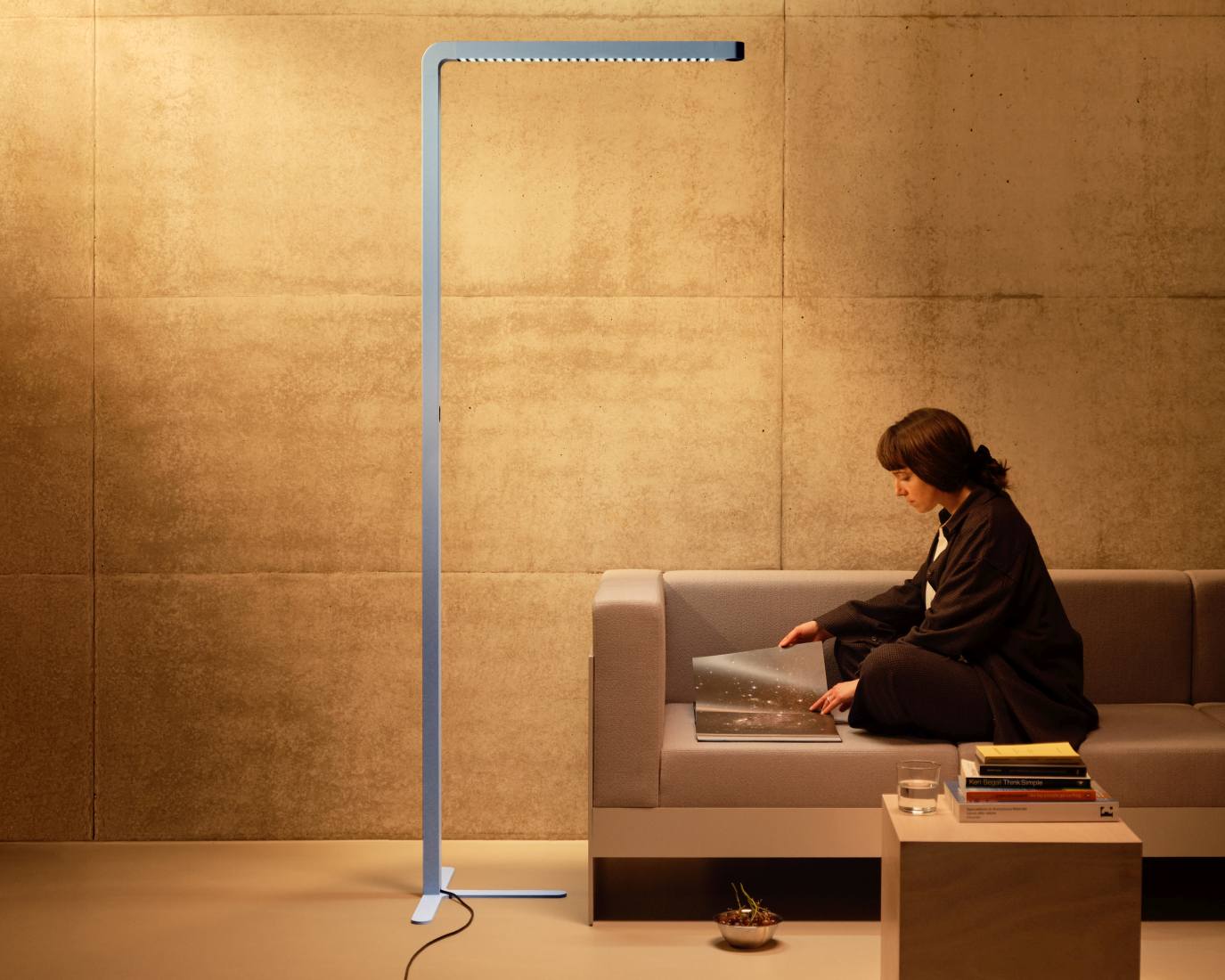 Team Agile Stehleuchte in Grau: Moderne LED-Stehlampe neben einer Frau auf einem grauen Sofa.