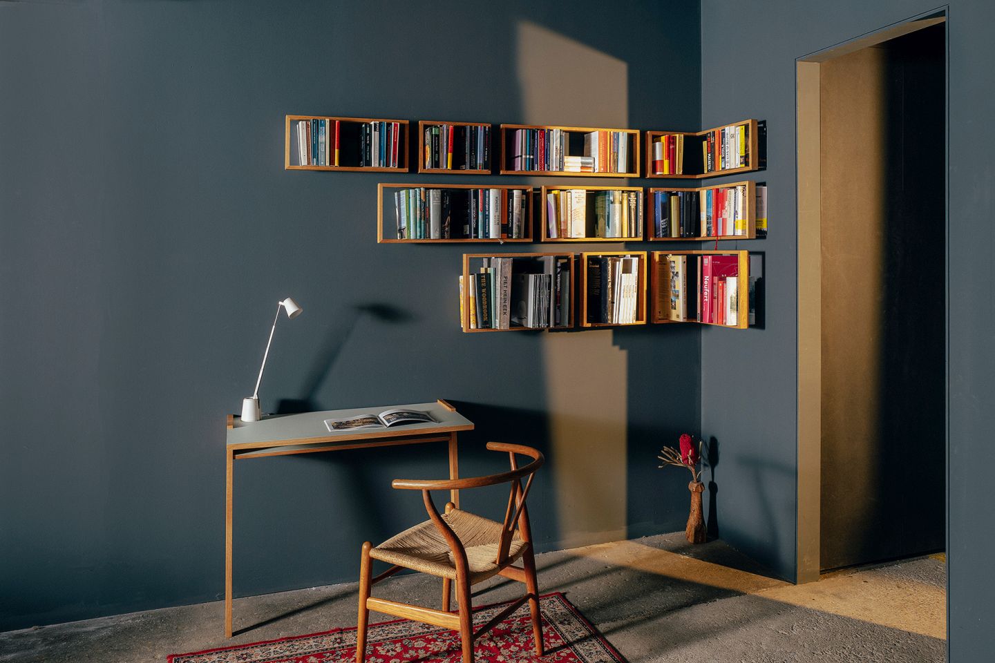 Wohnzimmer mit Regal b Eiche, Schreibtisch, Stuhl und Teppich für gemütliches Wohnen und Arbeiten.