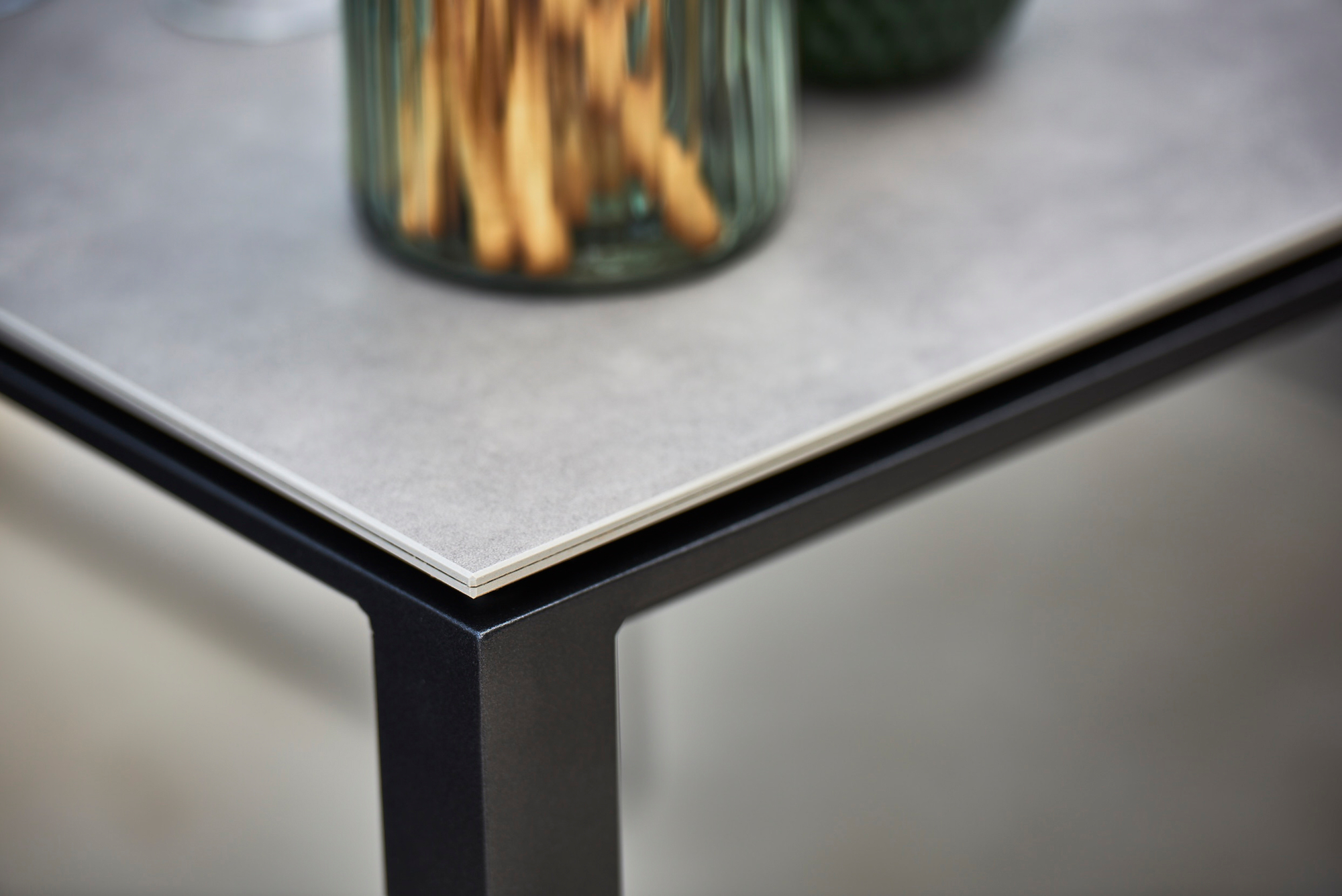 Detailaufnahme des Pure Outdoor Esstisches mit betongrauer Platte und hellgrauem Cane-Line Gestell. Moderner Gartentisch.