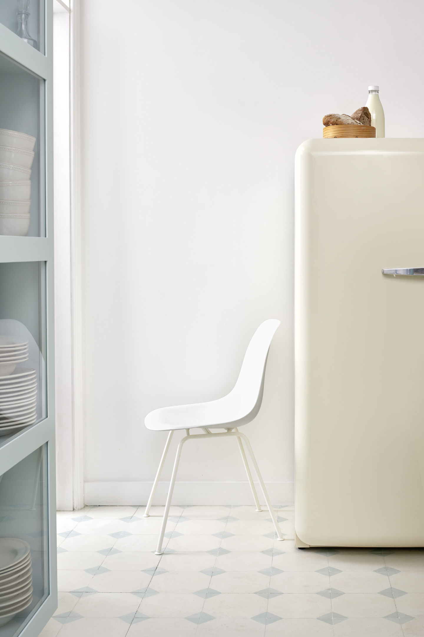 Weißer Eames Stuhl DSX von Vitra im minimalistischen Küchendesign mit Kühlschrank und Geschirr.
