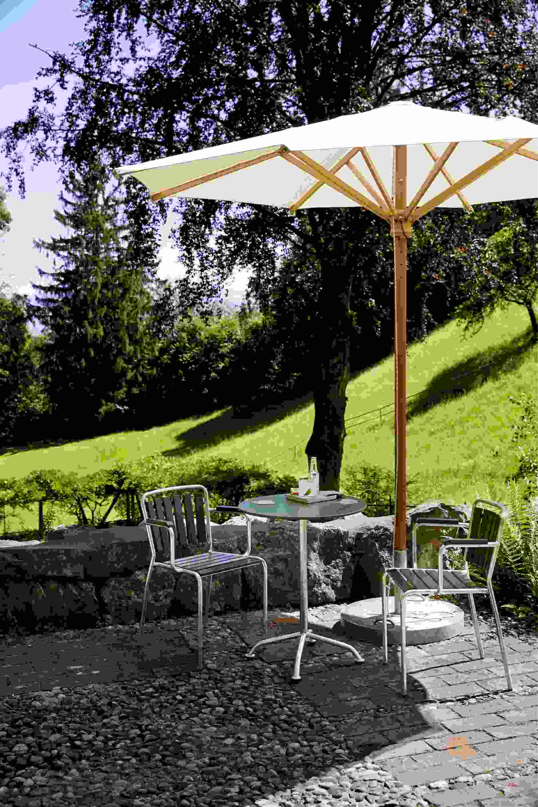 Haefeli Gartentisch, Outdoor Tisch weiß mit Sonnenschirm und zwei Stühlen im Garten.