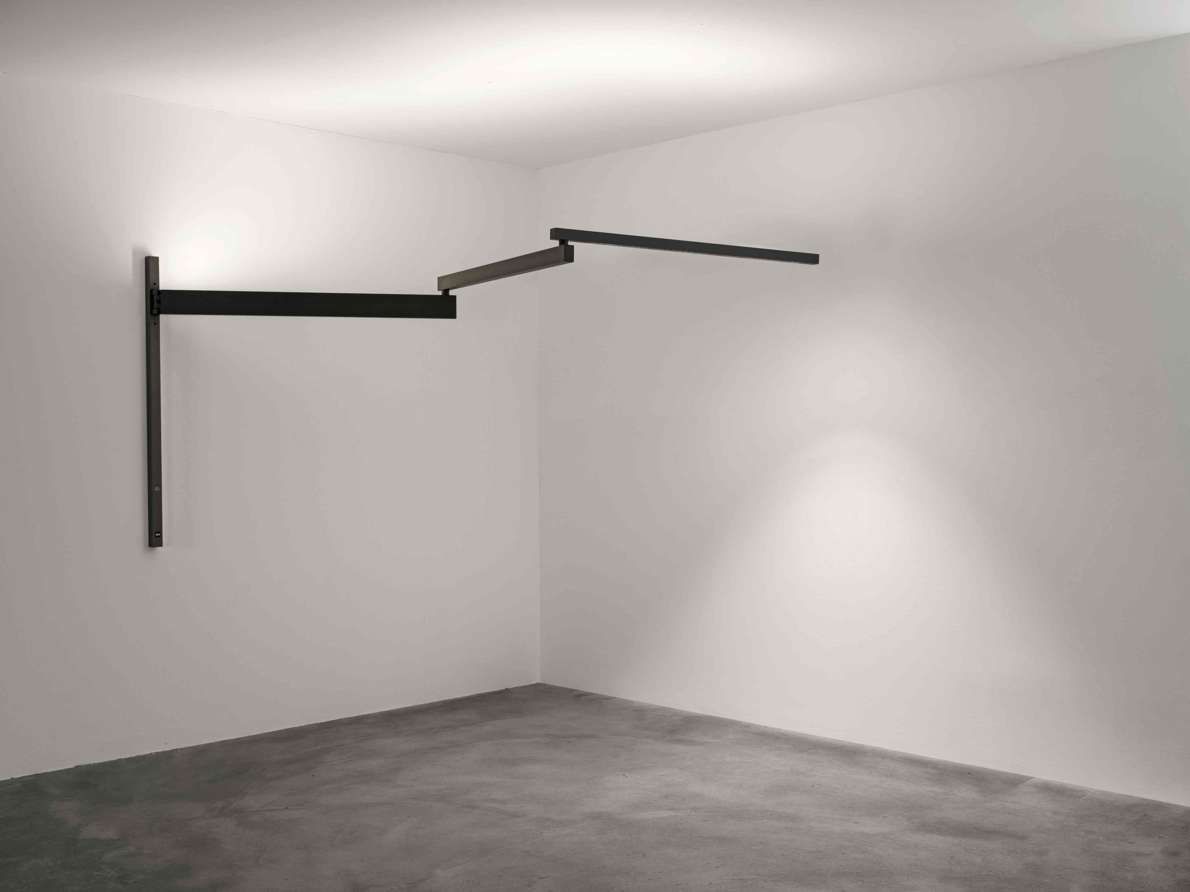 Schwarze Flos Wandleuchte "Black Flag" im minimalistischen Design, montiert an einer weißen Wand in einem leeren Raum.